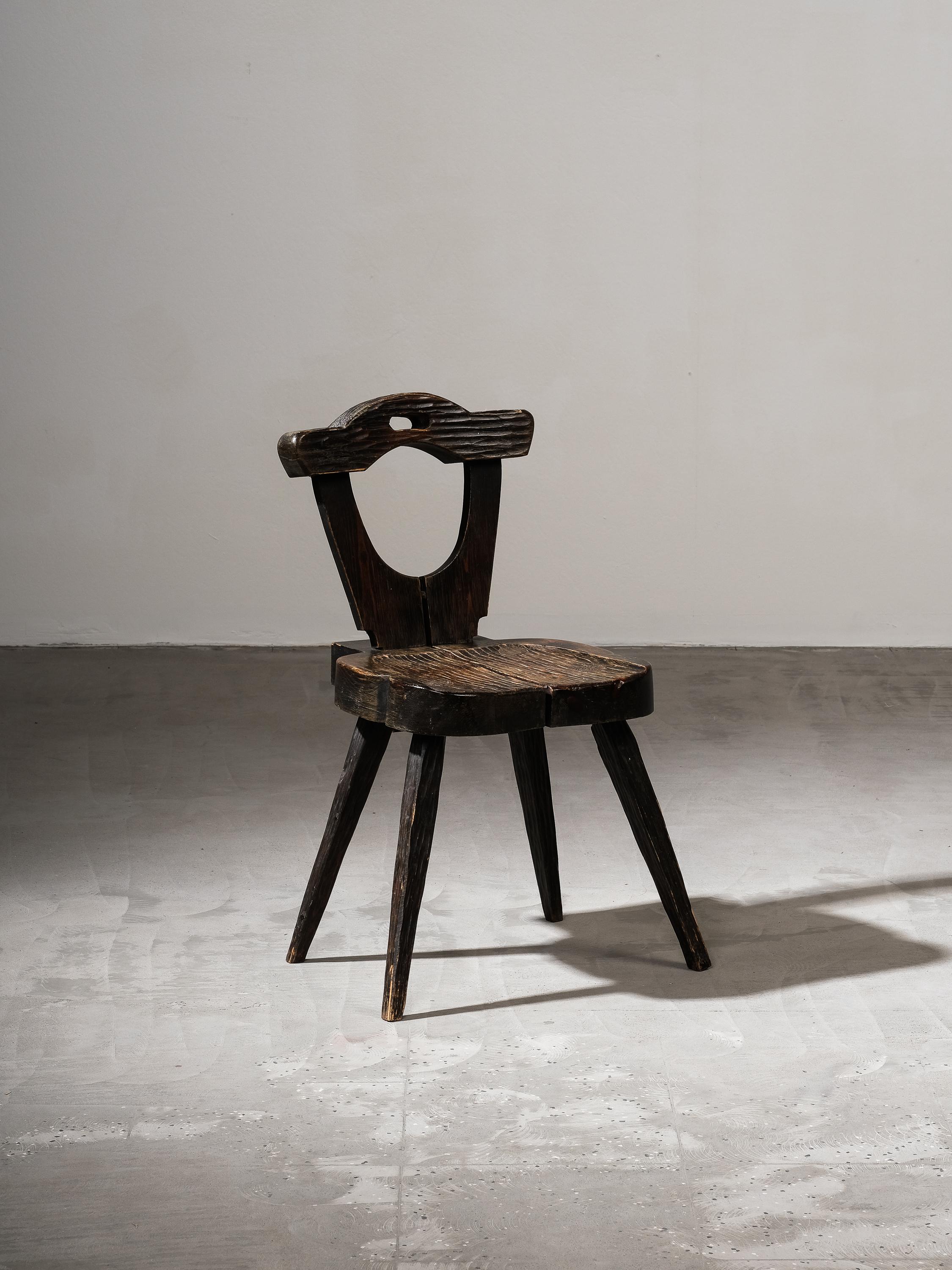Silla de arte popular finlandés fabricada a finales del siglo XIX. La silla está hecha a mano en madera de pino, con el asiento y el respaldo bellamente esculpidos. Las patas, el asiento y el respaldo vertical tienen un intrigante dibujo ondulado