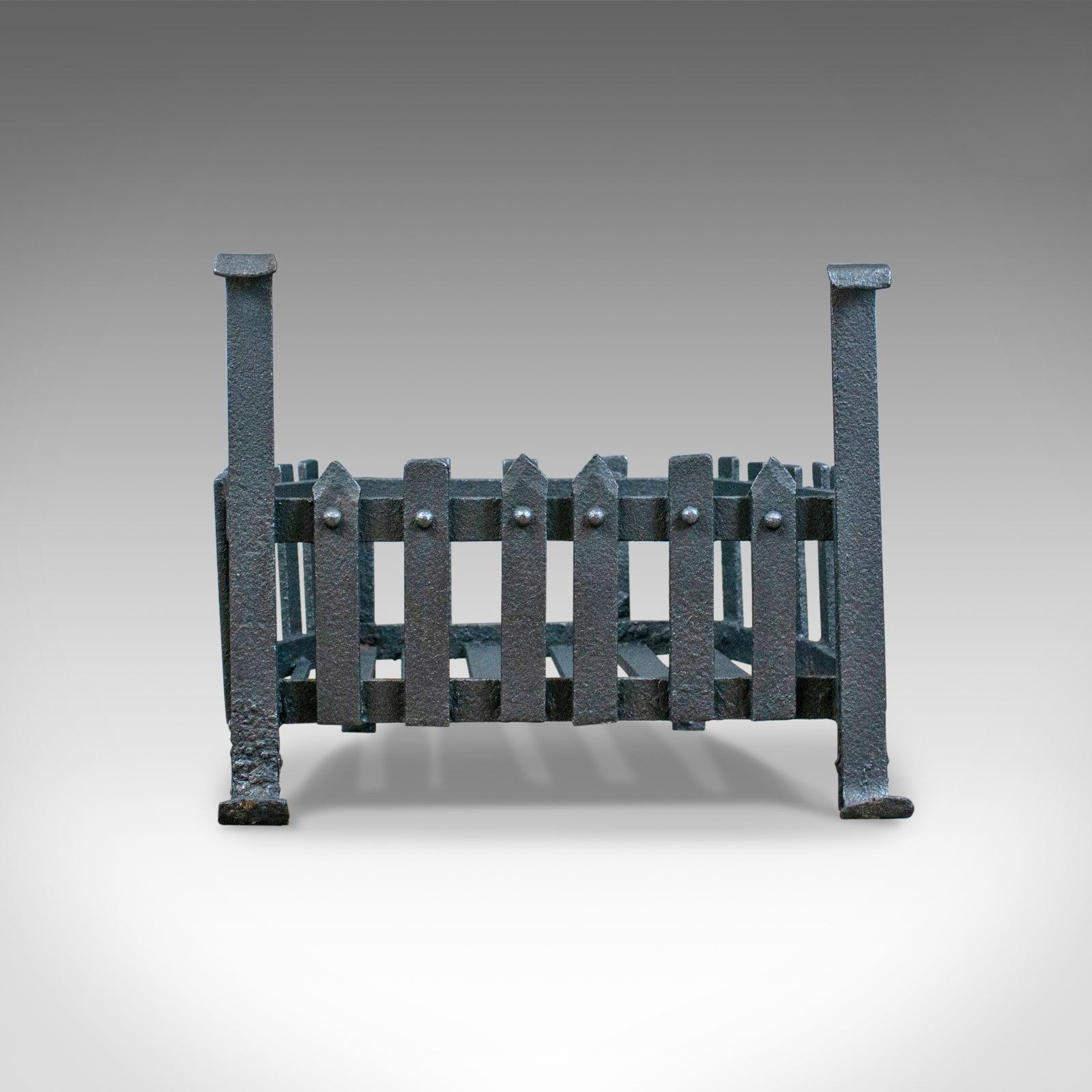 This is an antique fire basket, a free-standing Victorian fireplace grate in iron dating to the late 19th century, circa 1900.

Mid-sized, shaped at the rear to fit snugly into aperture
Suitable for all fuel types
In hand forged iron with dark