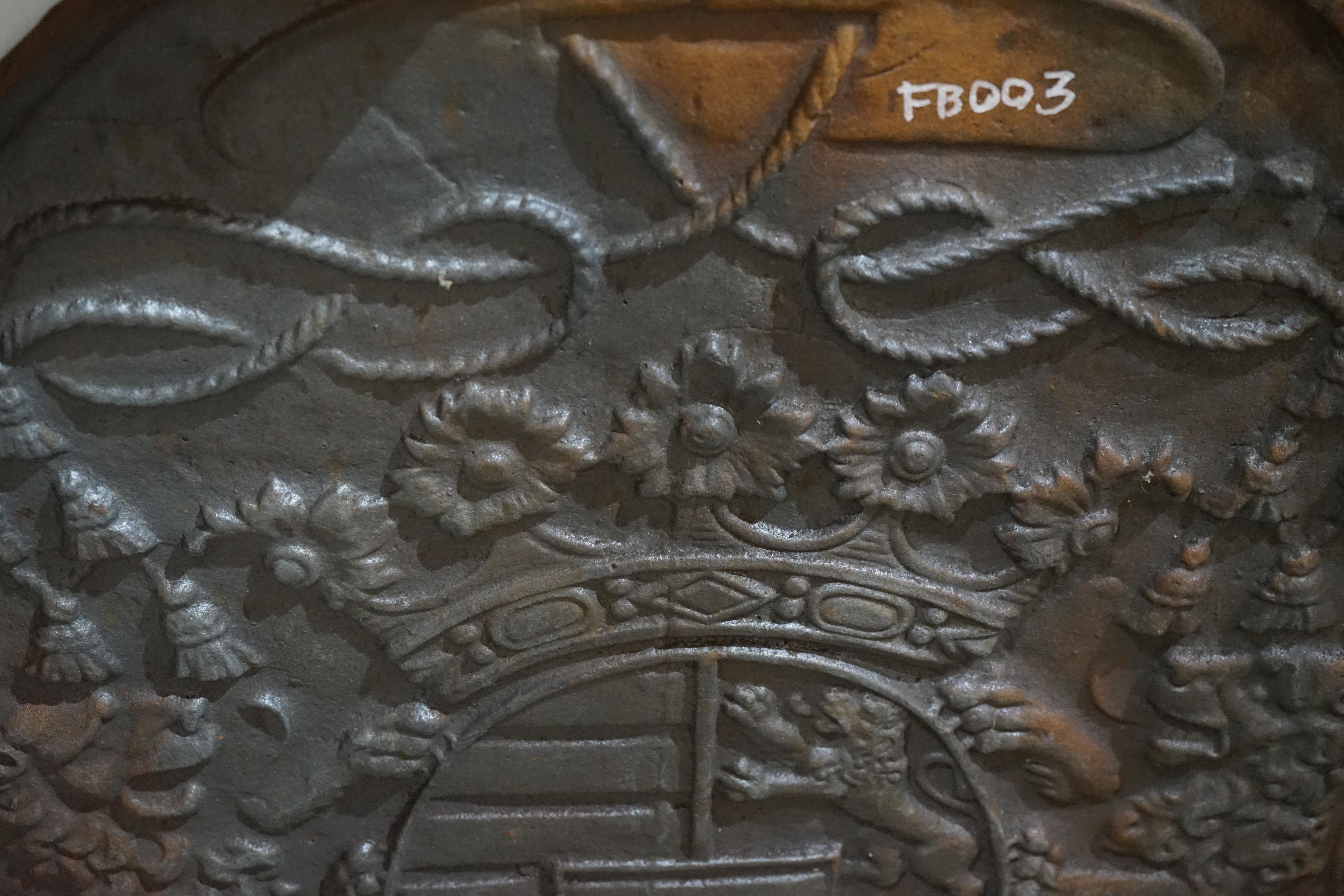 This antique fireback features a royal coat of arms with text 