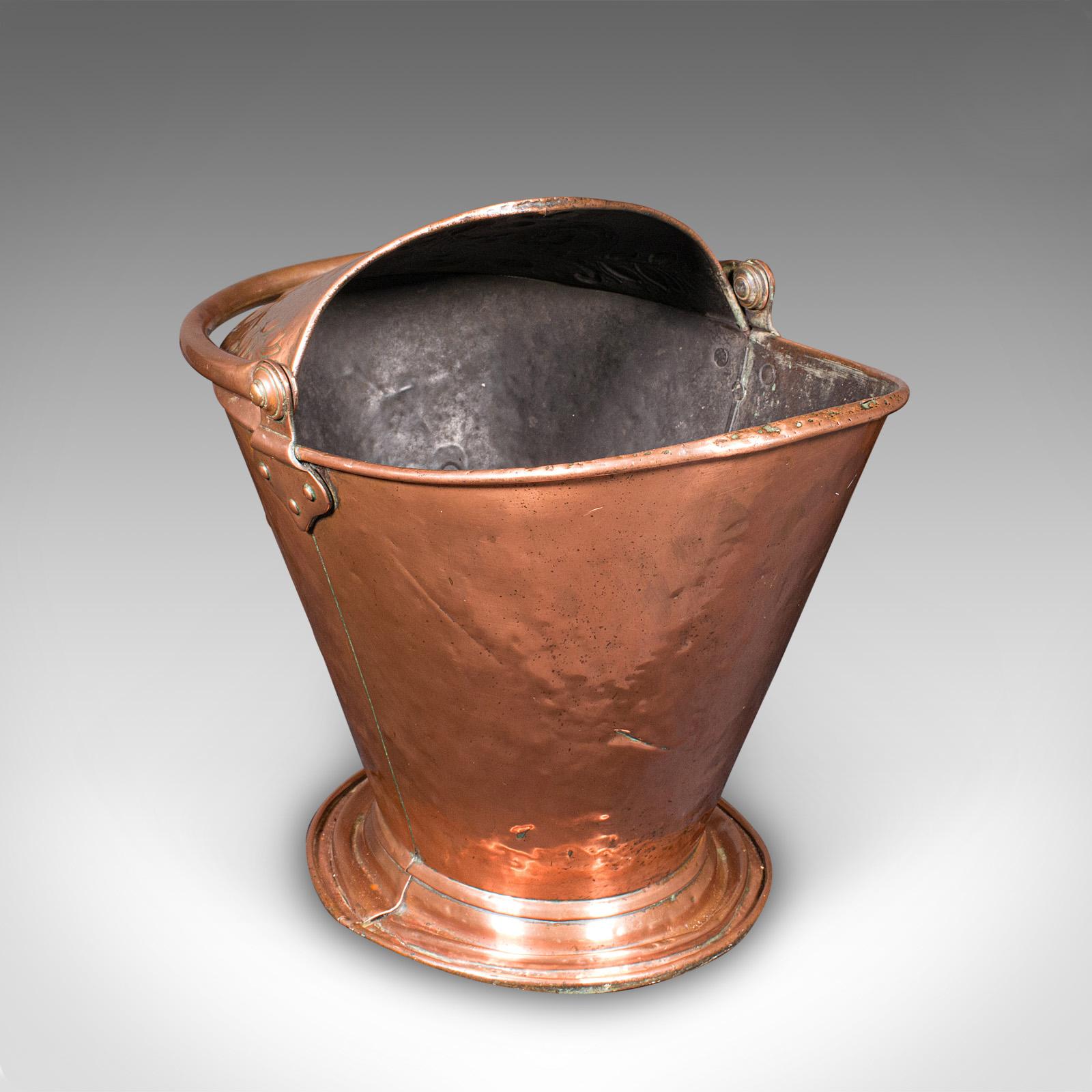 Si tratta di un'antica griglia per il carbone del caminetto. Un cesto da fuoco inglese in rame di gusto Art Nouveau, risalente al tardo periodo vittoriano, circa 1900. Un esempio di charme decorativo con un elegante profilo a cappuccio e calde