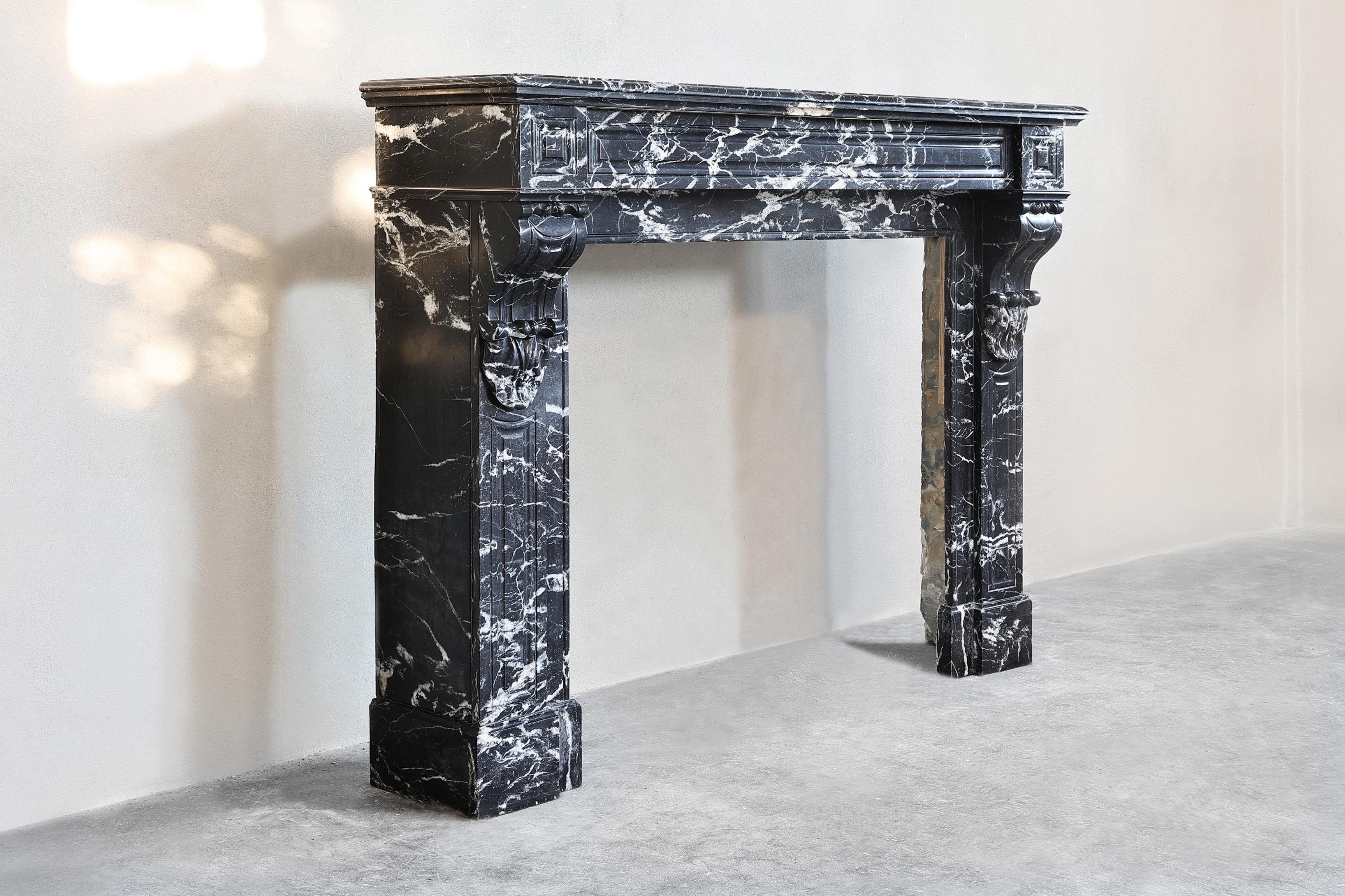 Beautiful antique marble mantelpiece made of Nero Marquina marble from the 19th century. This black marble with white veins gives a chic and timeless look. This mantle in the style of Louis XVI has a sleek shape and has fluting on the legs, but few