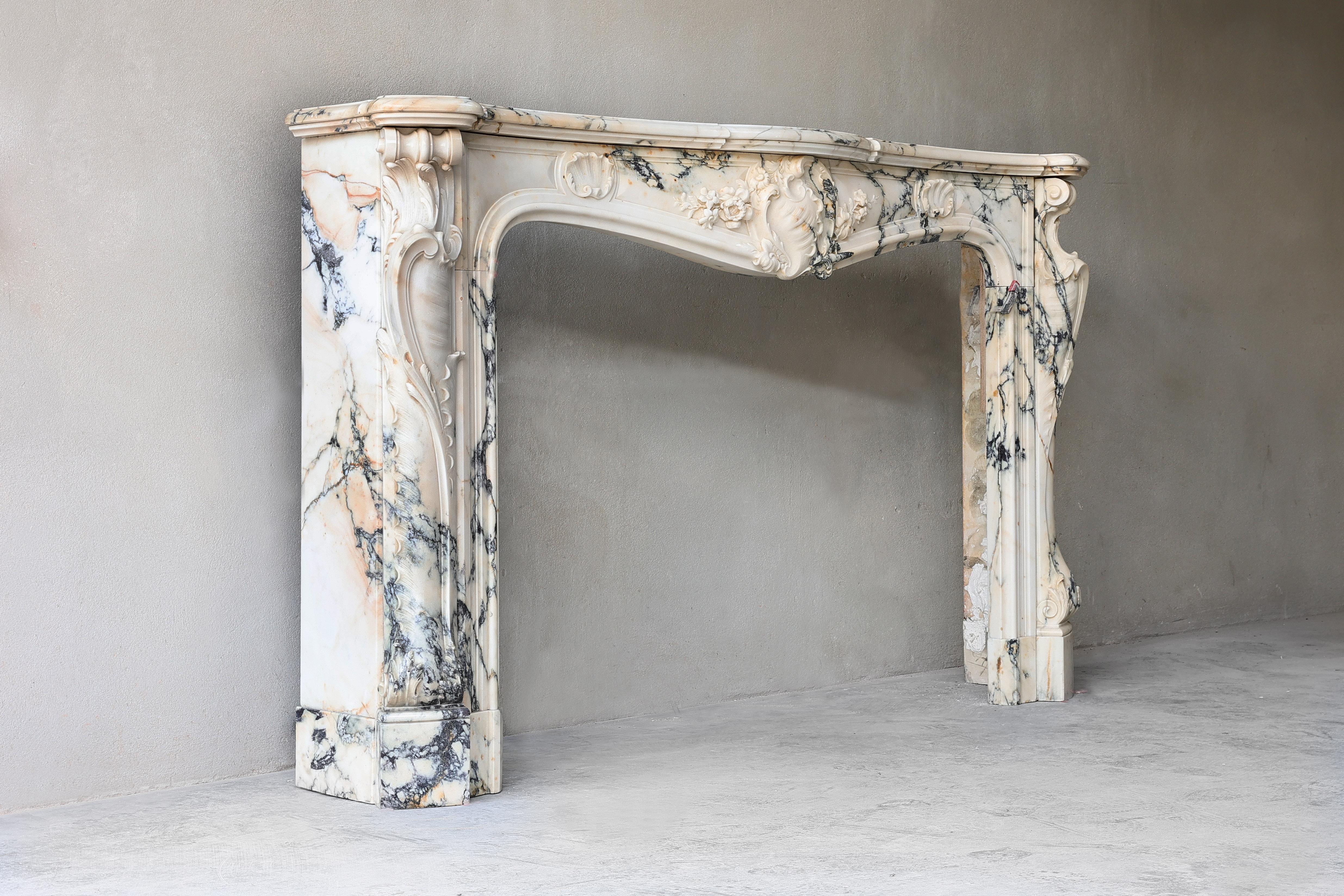 A very exclusive antique Paonazzo marble fireplace from 1820! This rare type of marble comes from Italy - Tuscany and has a colorful collection of color tones. The fireplace is in Louis XV Rococo (Rocaille) style , characterised by its asymmetric