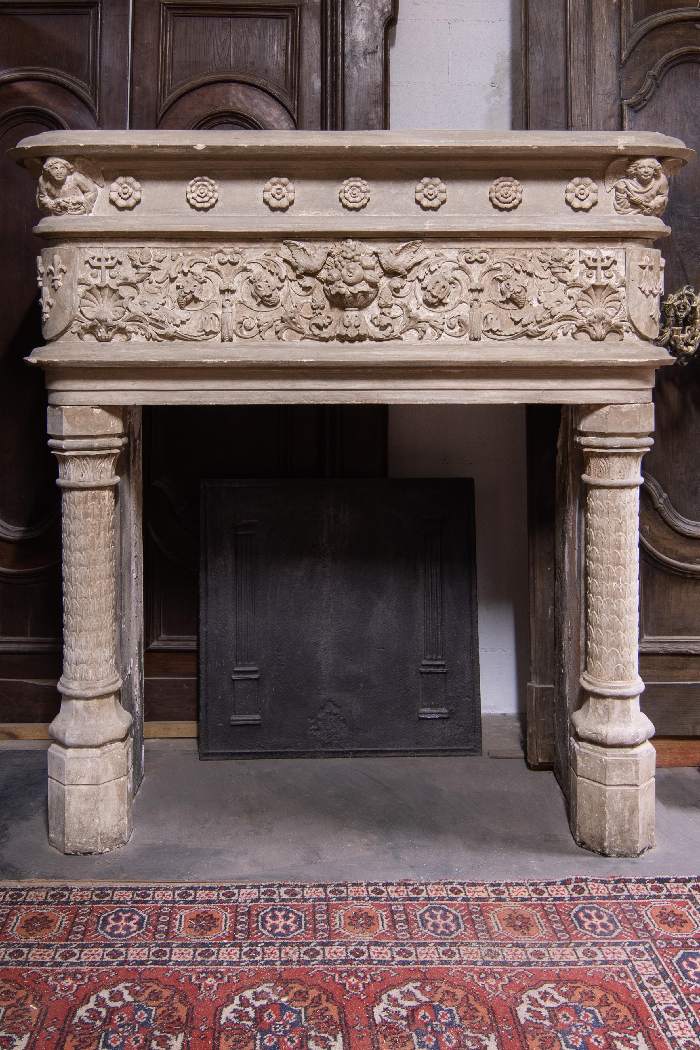 Cheminée ancienne en pierre grise, sculptée à la main avec diverses figures d'oiseaux, de fleurs et de putti, très riche en décorations, avec des boucliers et des lys dans les coins, elle provient d'un ancien château en Italie dans les années