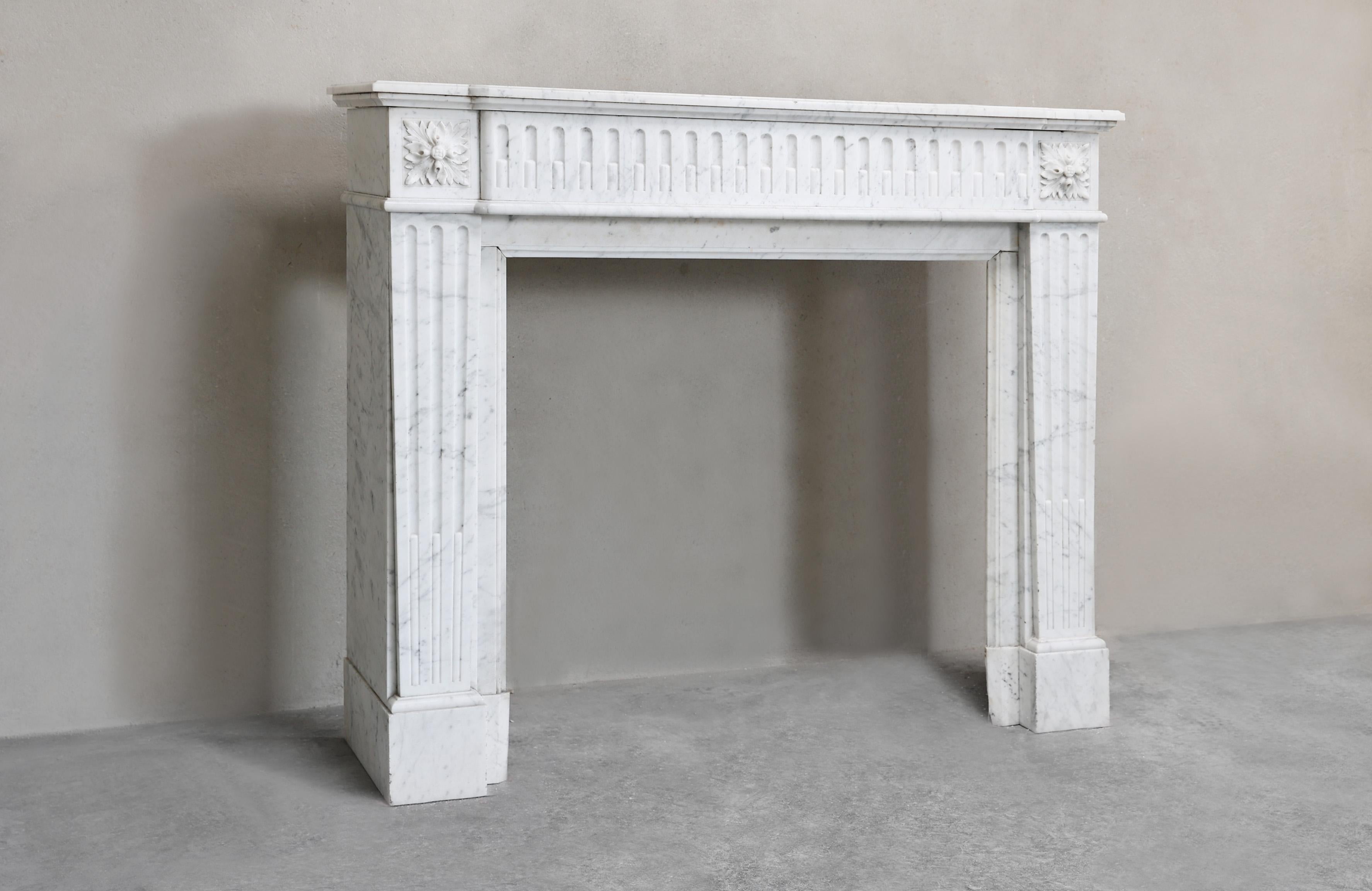 Bellissimo camino antico del XIX secolo in stile Luigi XVI, realizzato in marmo di Carrara di alta qualità. Questo caminetto antico ha una forma rettilinea, caratterizzata da linee rette, simmetria e una ricca scanalatura che conferiscono a questo