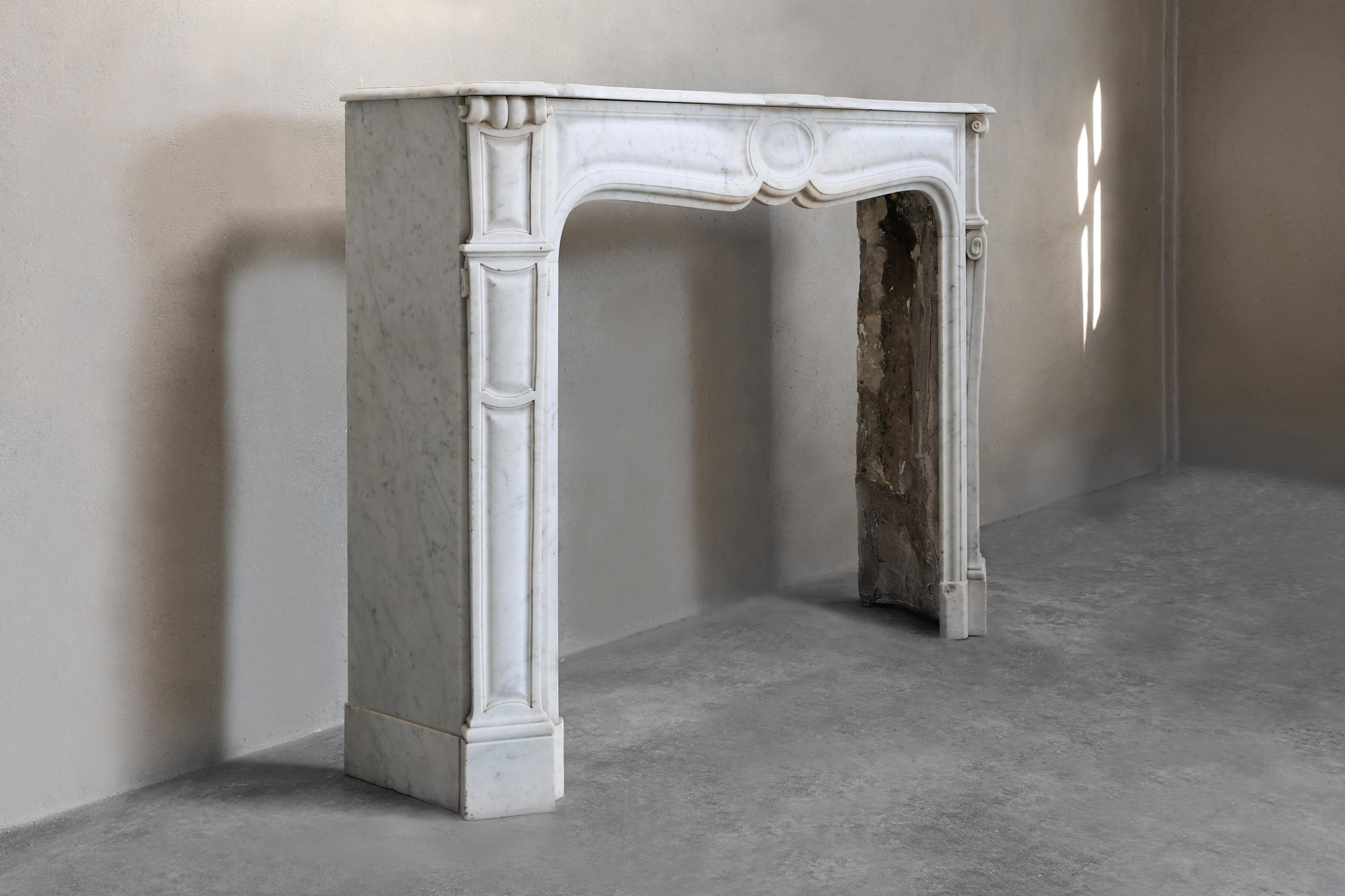 Bellissima mensola compatta e antica in marmo di Carrara proveniente dall'Italia. Questo elegante camino risale al XIX secolo e presenta bellissimi ornamenti e linee sottili sulle gambe. Una mensola Pompadour è caratterizzata da un ornamento rotondo