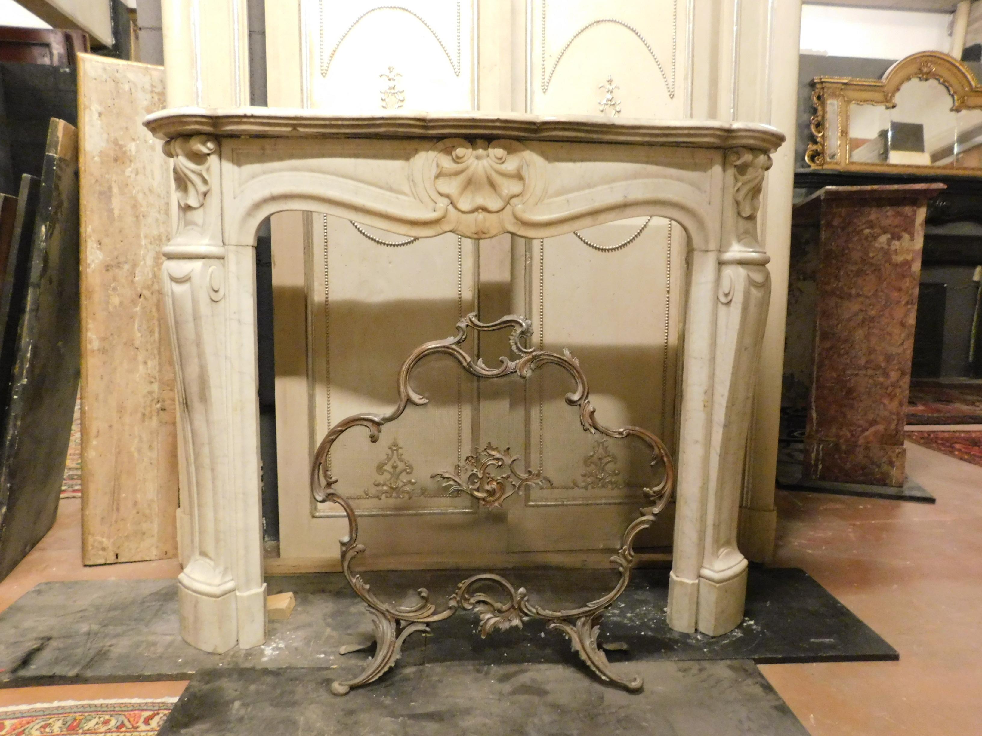Antique fireplace in white Carrara marble, hand carved with three shells (central and side) and lucky bell. It has wavy legs, but has some smoke and fire stains, which are difficult to remove, so the coat is depreciated compared to the excellent