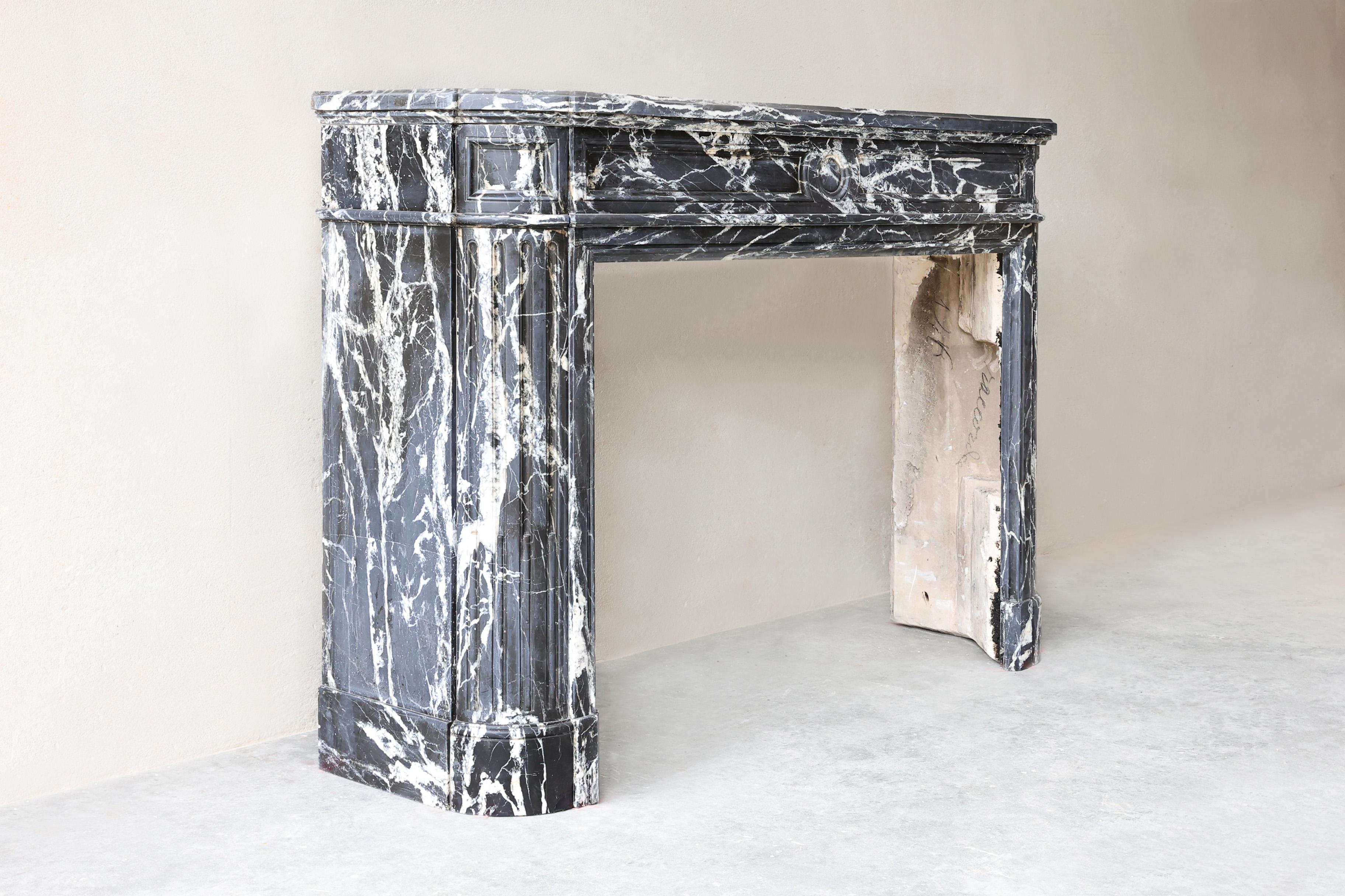 Antique Nero Marquina Fireplace in Louis XVI Style 

This rare antique fireplace made from Nero Marquina marble is a stunning example of the refined Louis XVI style from the 19th century. The deep black marble with dramatic white veining exudes