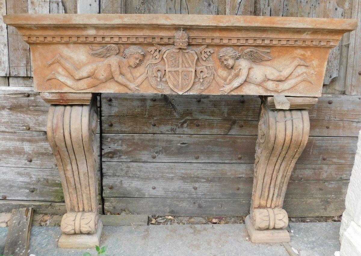 Antique fireplace mantle in terracotta, richly carved with a pair of cherubs holding a noble coat of arms, composed in the early 1900s in Tuscany, Italy.
maximum measurements cm W 136 x H 114 x T 32, internal opening cm W 79 x H 82.
Ideal for
