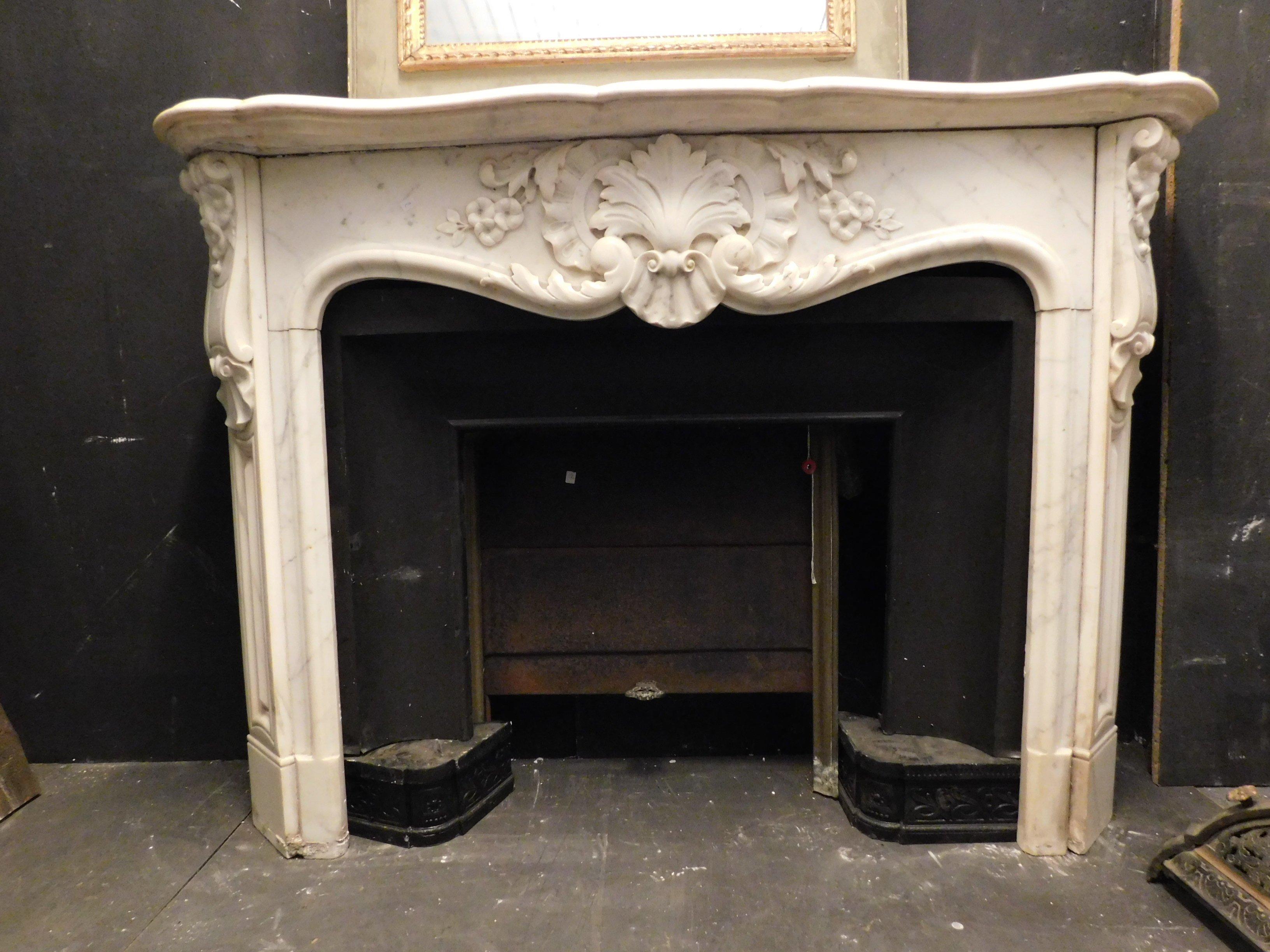 Antique fireplace mantel (fireplace) in white Carrara marble, richly carved with central shells and rigolini, floral motifs, all carved by hand and with a black heart (internal part), beautiful vents on the sides in gilded brass, produced by a