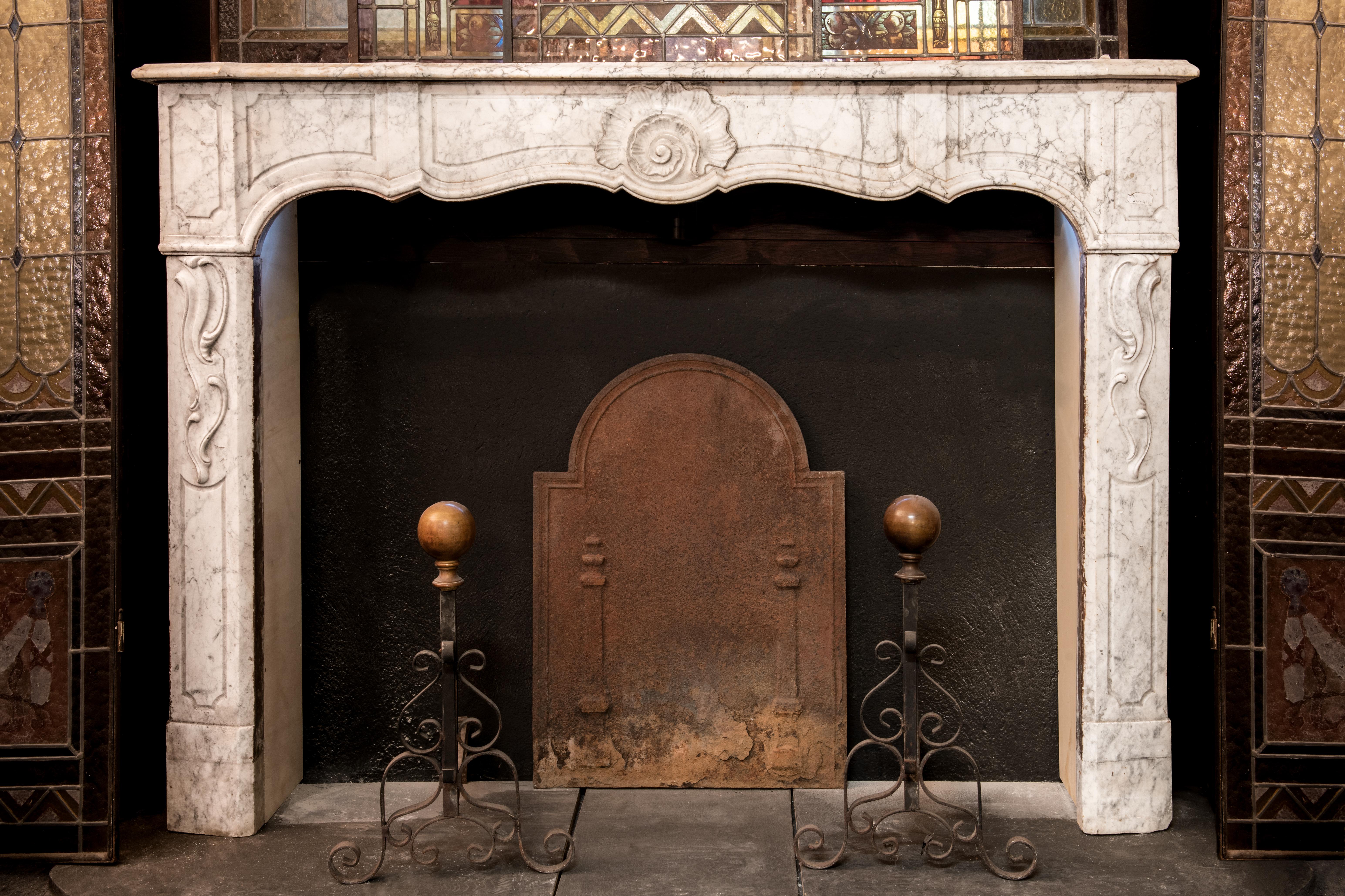 Antique fireplace in white Carrara marble, hand-carved mantle with central shell and decorations on the legs, built entirely by hand in Italy in the 1700s, from Genoa.
It has no sides because that part was originally made of bricks in the