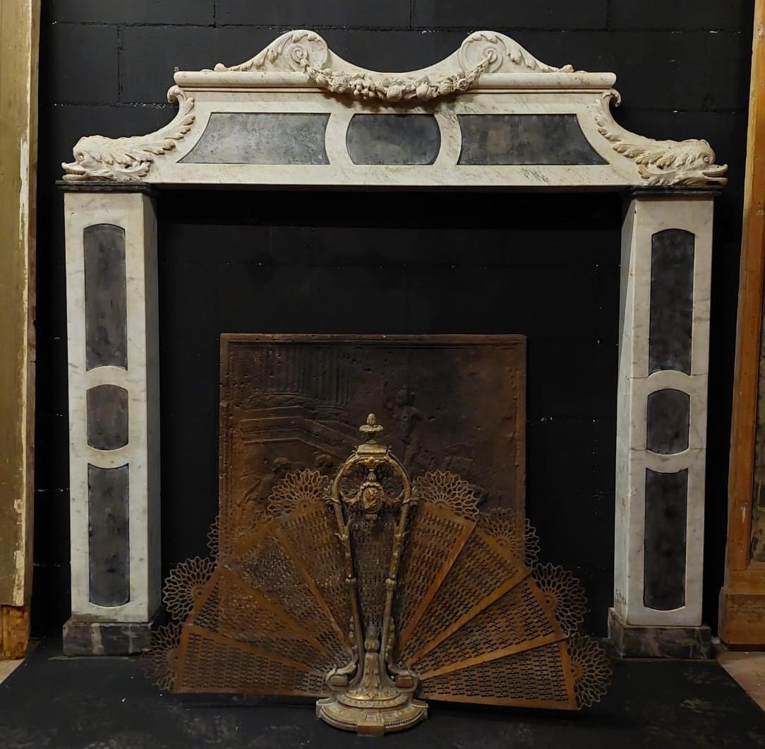 Antique fireplace mantle in white Carrara marble with carved tritons / dolphins and slate inlays, built and sculpted entirely by hand in the 19th century, from Genoa (Italy), of great value and manufacture, one of a kind, very well preserved and of