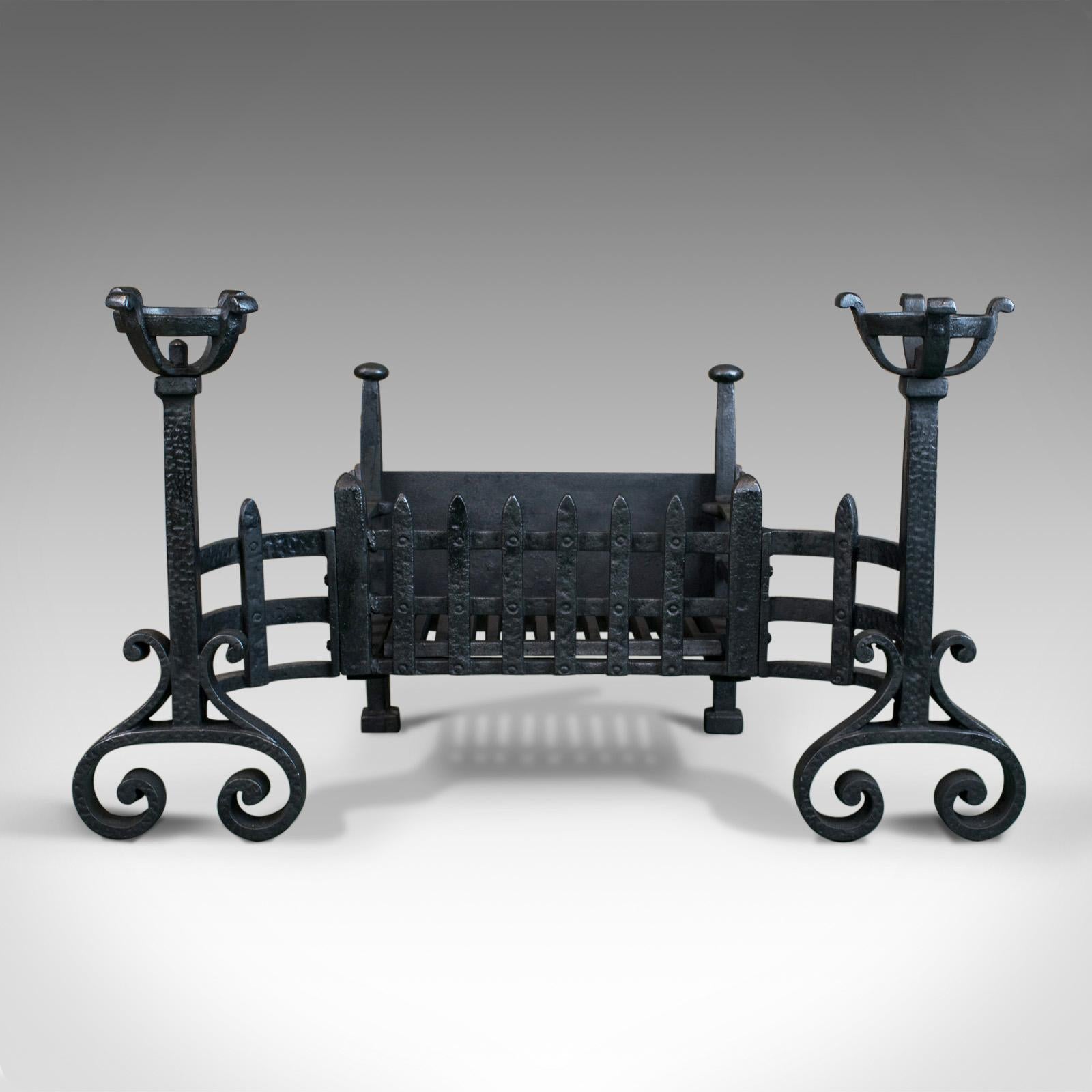 This is an antique fire basket. An English fire grate in the medieval-revival taste featuring cup-dogs. Hand forged in iron at the turn of the century, circa 1900.

Pleasing fire basket in traditional form
Benefitting from cup-dogs for warming