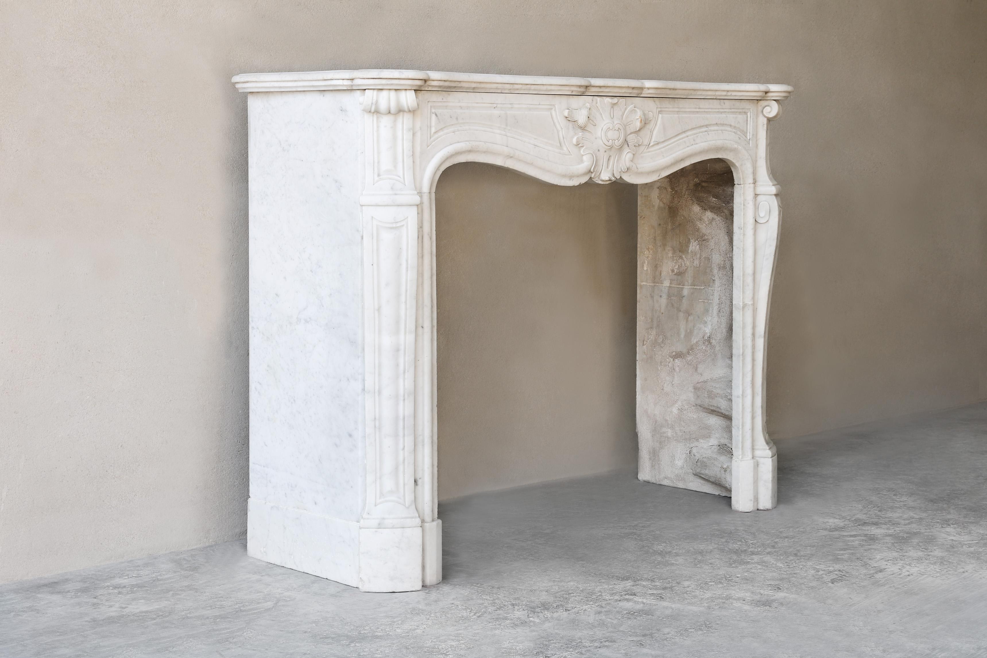 Schöner schicker antiker Kaminsims aus Carrara-Marmor aus dem 19. Dieser Kaminsims ist im Stil von Louis XV und hat ein schönes Ornament in der Mitte des vorderen Teils. Die schönen runden Linien an den Beinen sorgen für ein elegantes und warmes