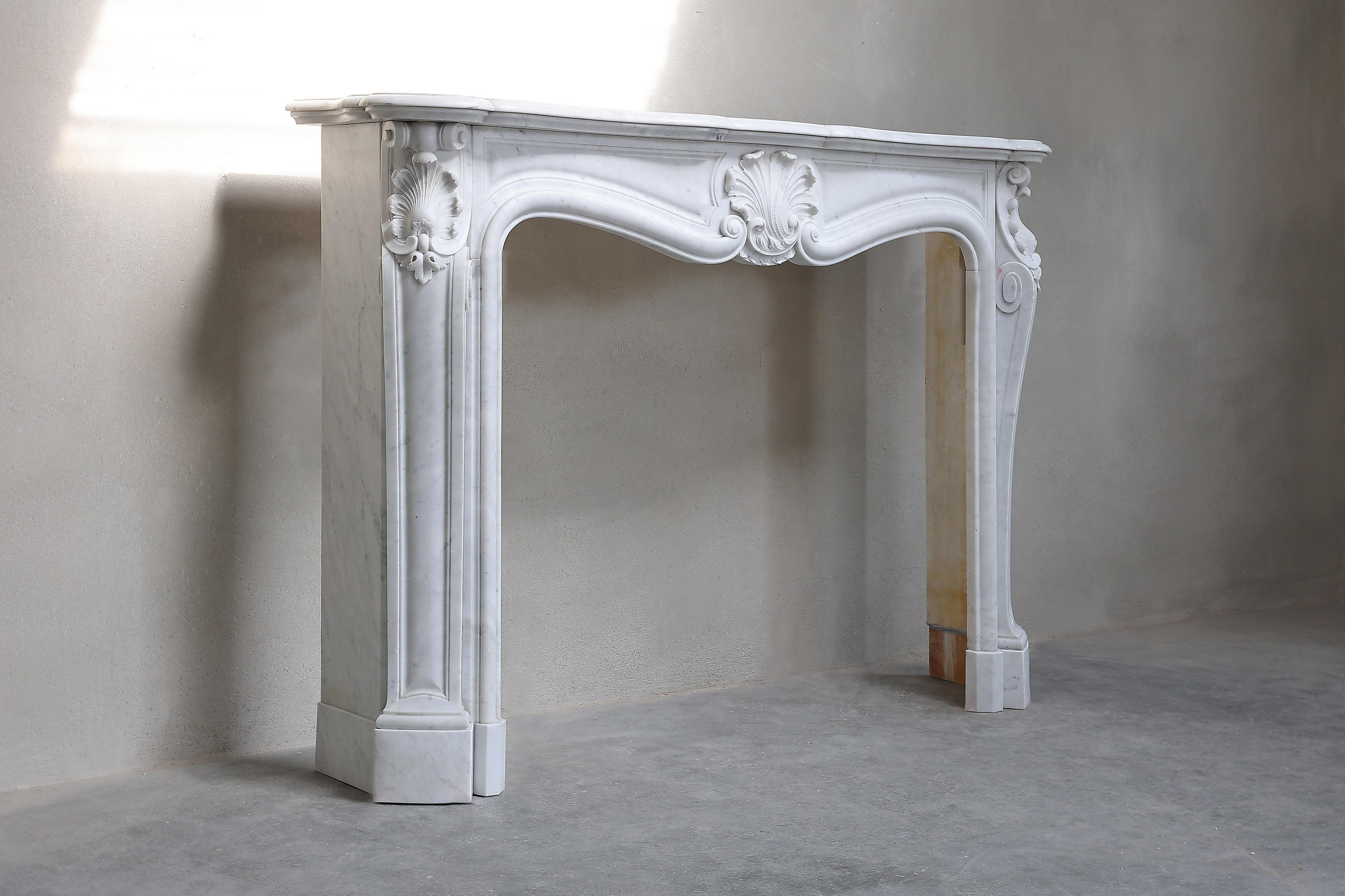 Schöner antiker Kamin aus weißem Carrara-Marmor aus dem 19. Jahrhundert. Der Kamin ist im Stil Ludwigs XV. gehalten und hat in der Mitte und an den Seiten eine Jakobsmuschel, auch 
