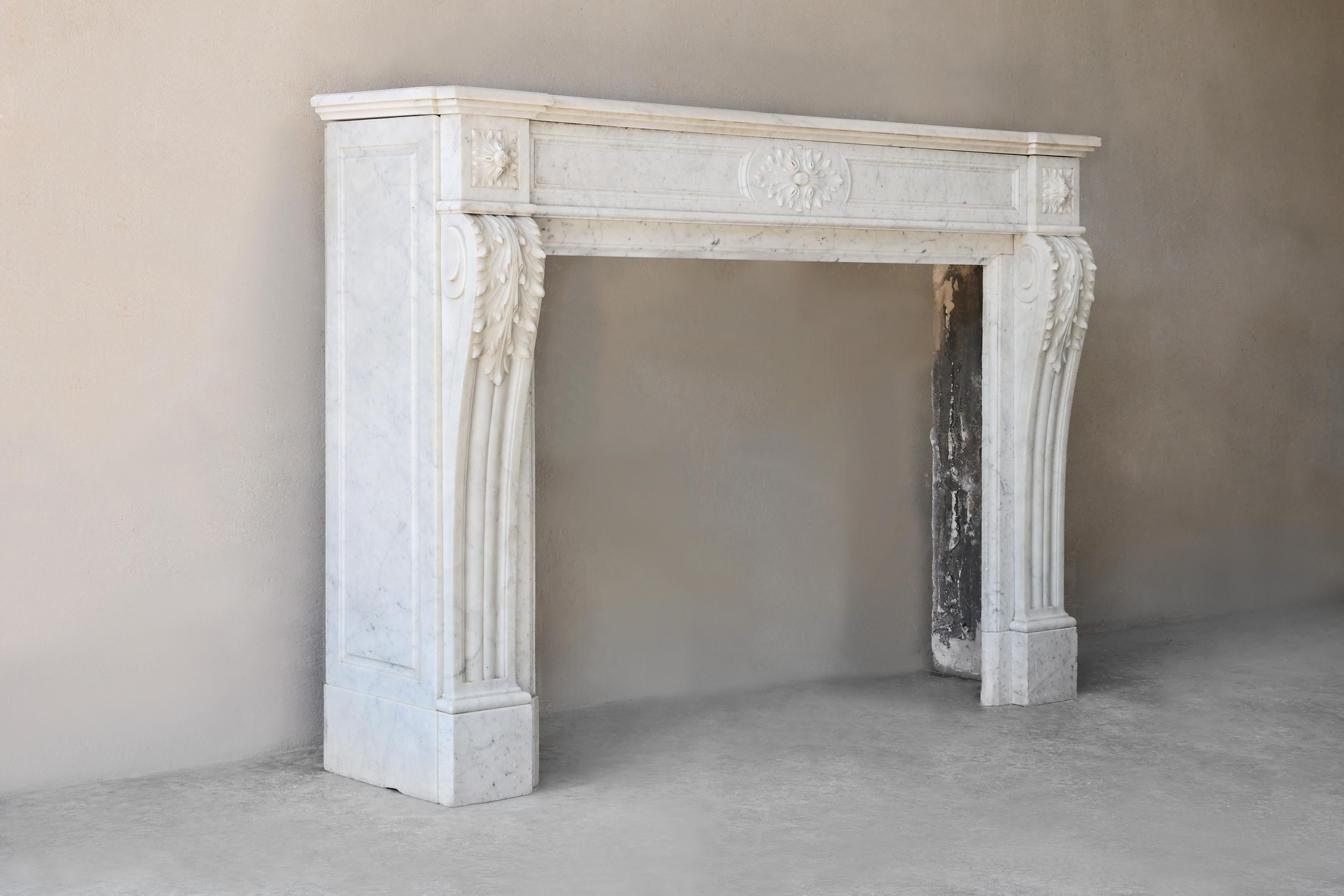 Cette cheminée ancienne du XIXe siècle est réalisée en marbre de Carrare de haute qualité provenant d'Italie. Le design de style Louis XVI se caractérise par des lignes épurées, des détails gracieux et un médaillon classique. La cheminée respire