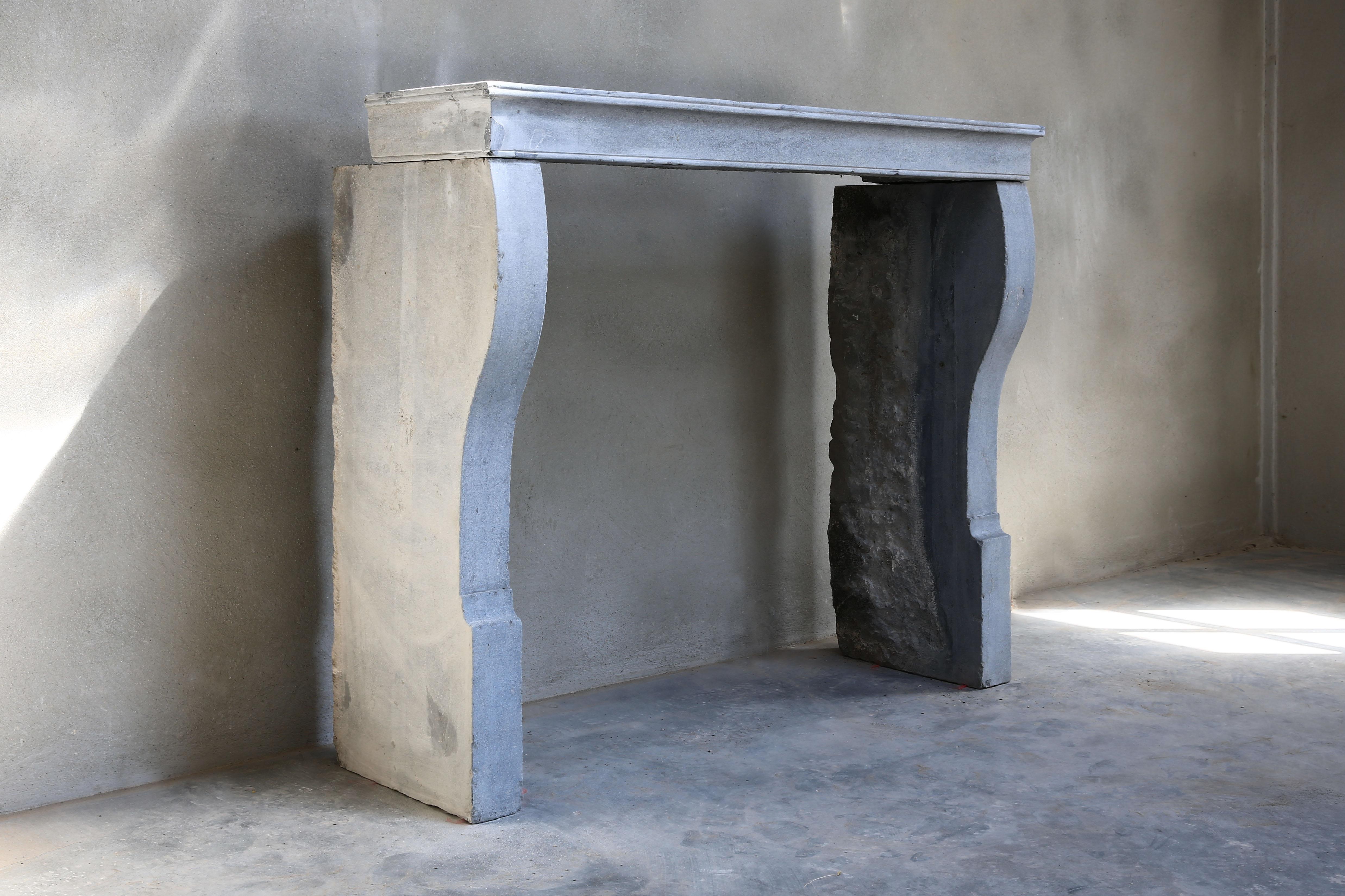 A beautiful and sober gray fireplace of marble stone in Campagnarde style, 19th century. The top is straight without decorations, but with a nice line. The legs, on the other hand, are slightly curved and give the fireplace something extra. We can