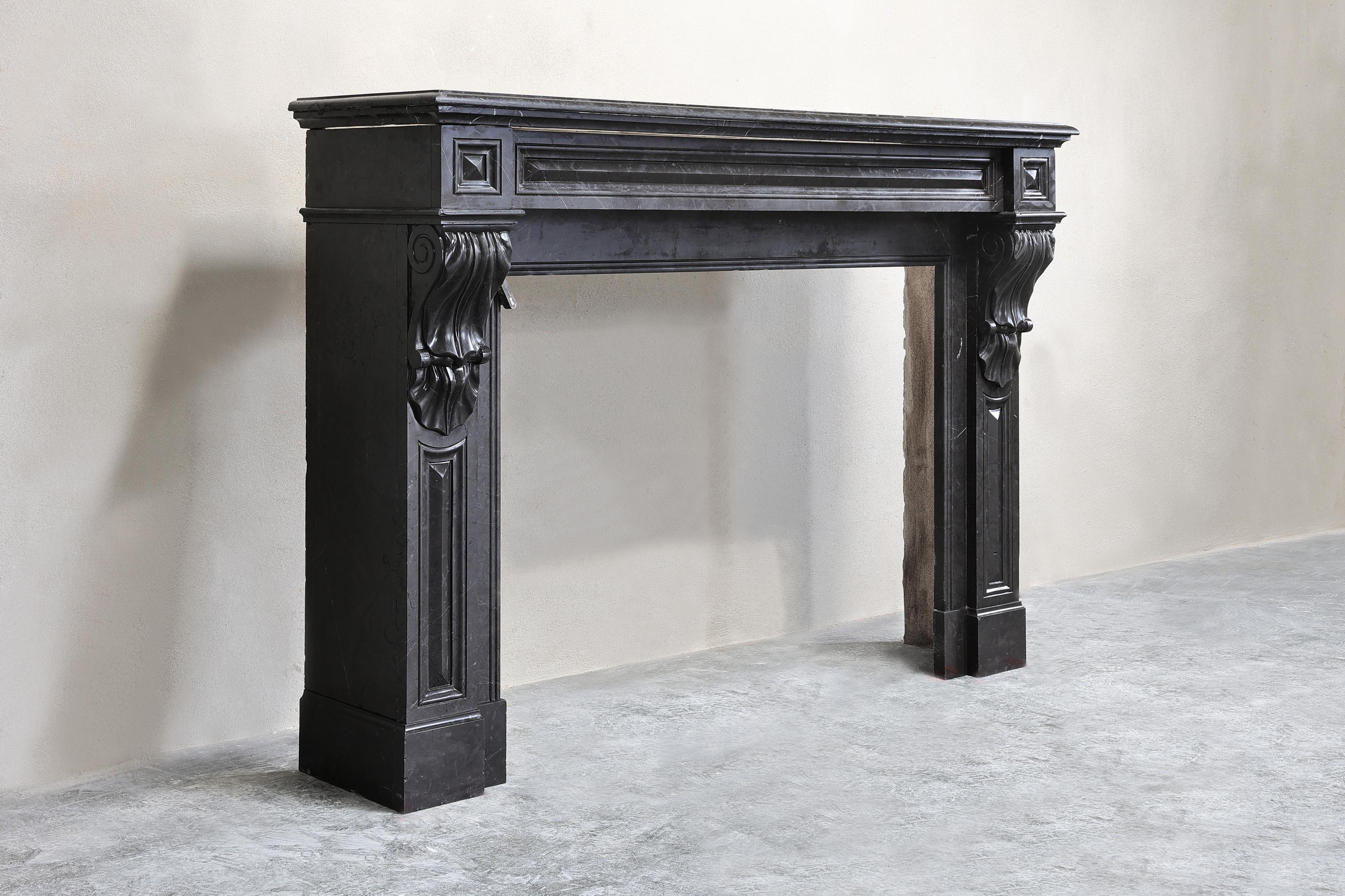 Beautiful antique mantelpiece made of Nero Marquina marble from the 19th century! This mantelpiece is in the style of Louis XVI and has beautiful ornaments in the front part and on the legs! A mantelpiece with a chic appearance and a nicely
