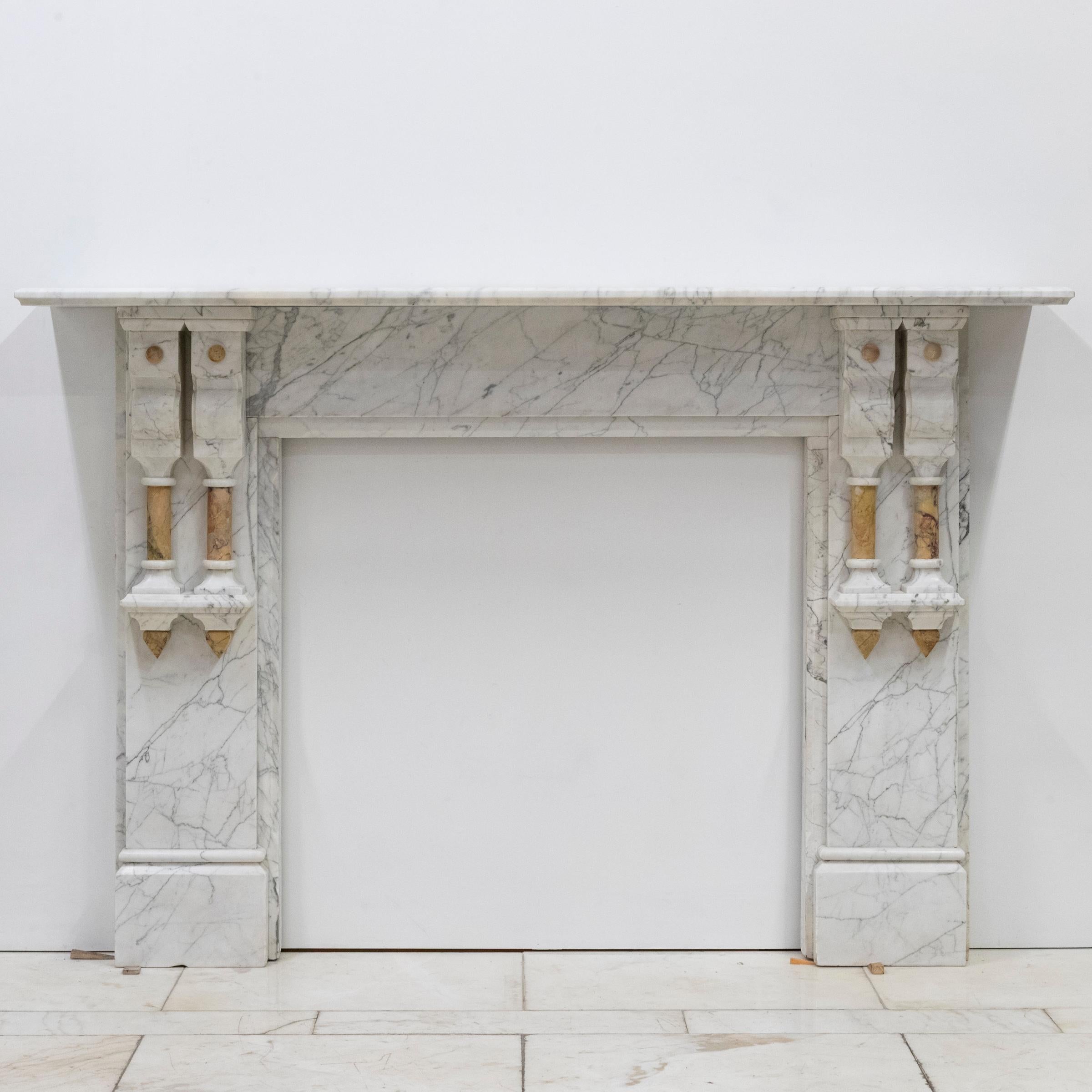 Se trata de un marco de chimenea antiguo finamente elaborado, ejecutado en mármol italiano de Carrara de alta calidad con un patrón clásico de vetas blancas y grises. El diseño refleja la influencia neoclásica de finales del siglo XIX, y se
