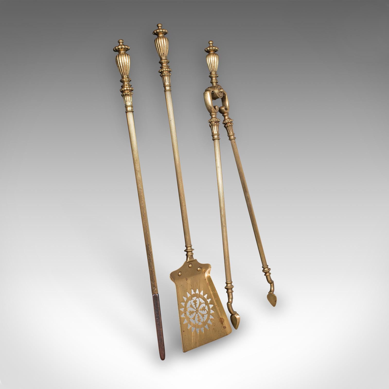 This is an antique fireplace tool suite. An English, brass shovel, poker and tong set with accompanying tool rests, dating to the mid Victorian period, circa 1870. An exceptional example of Victorian fireplace furnishing, offering refined