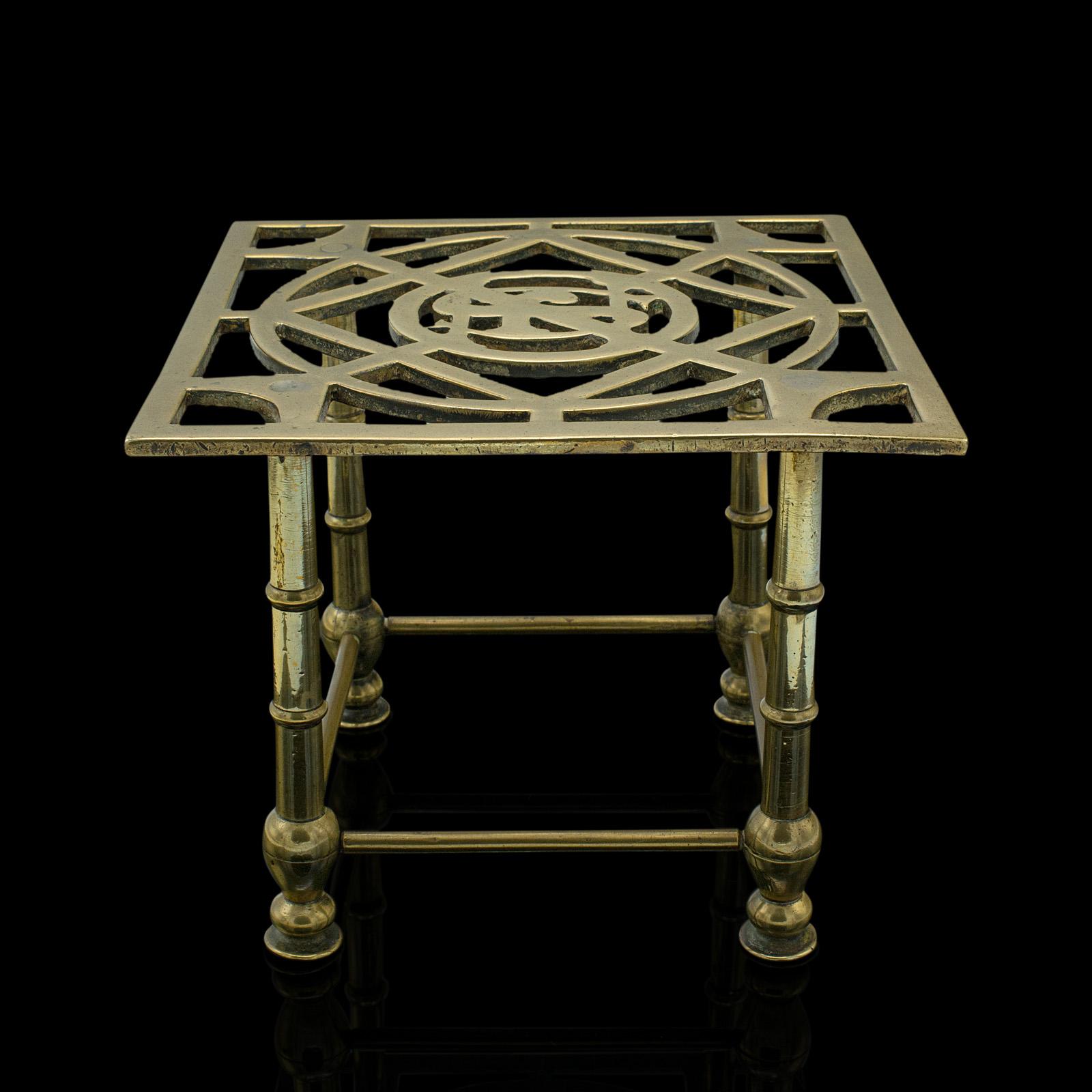 This is an antique fireside trivet. An English, brass kettle rest or decorative stand, dating to the late Victorian period, circa 1880.

Delightfully polished stand with skilful monogram to centre
Displays a desirable aged patina and in good