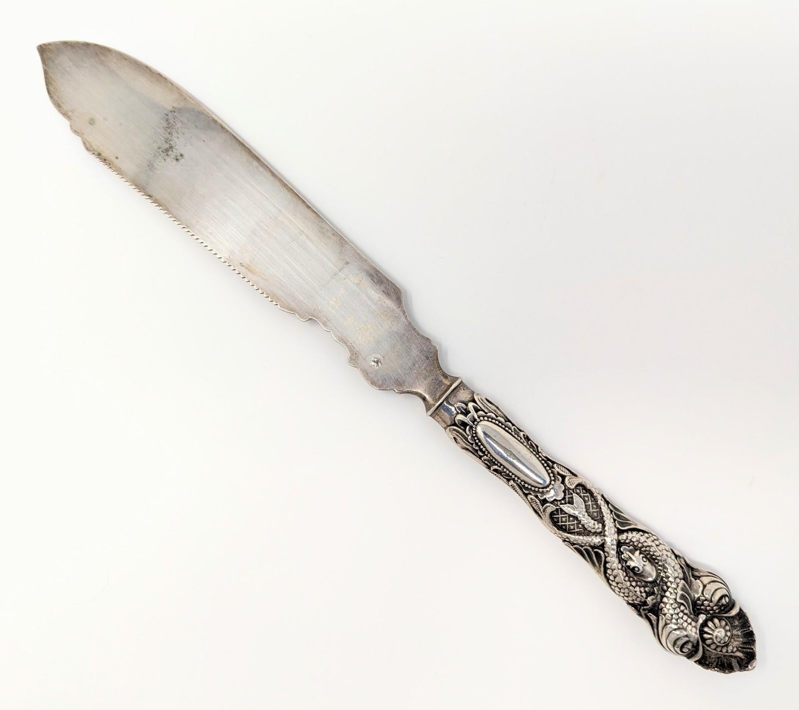 Stunning antique handcrafted fish or cake knife featuring unique sea serpent and shell pattern handle. The blade portion has intricate etchings, making this a wonderful piece of collectible art. Hallmarked on both sides of the blade as shown in the