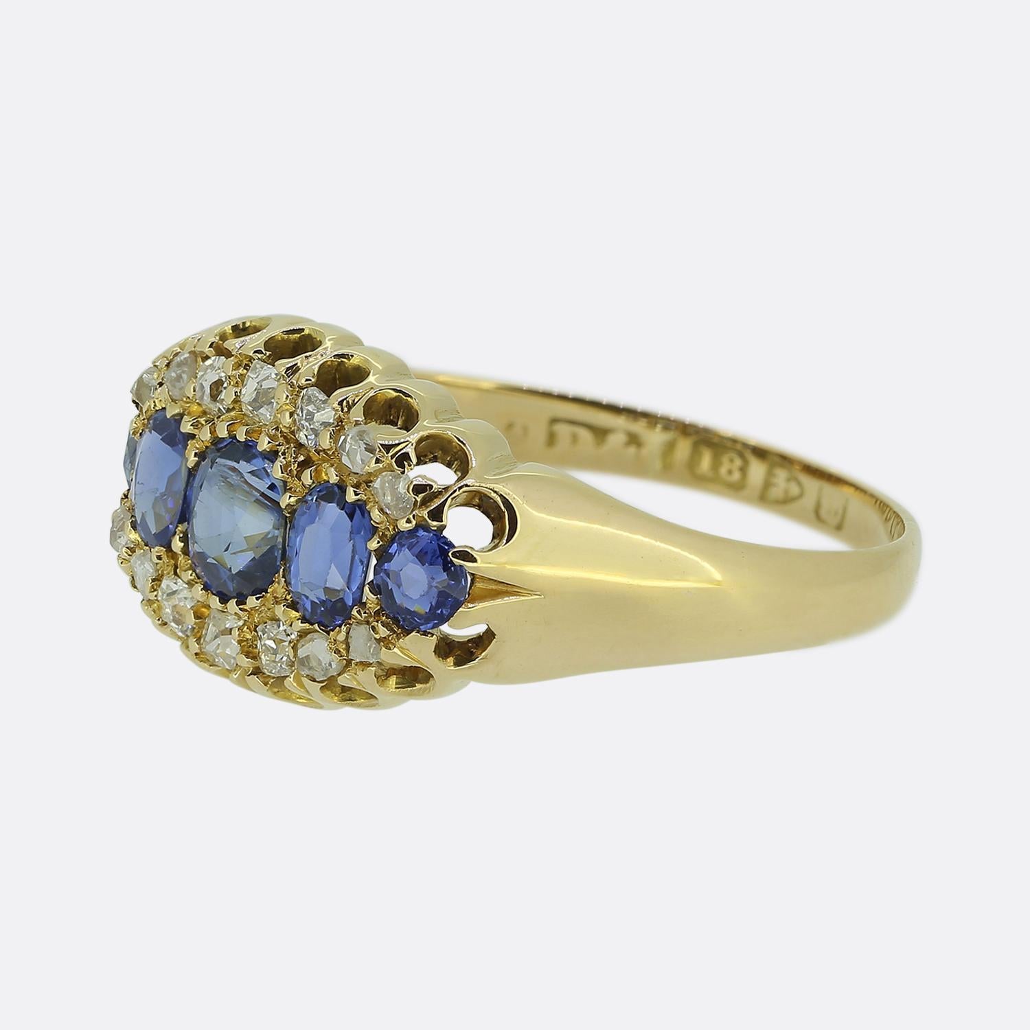 Hier haben wir einen schönen viktorianischen Ring aus 18 Karat Gelbgold. Das Design zeichnet sich durch eine zentrale Anordnung von kornblumenblauen Saphiren aus, die oben und unten durch eine Bordüre aus Diamanten im Altminen- und Rosenschliff