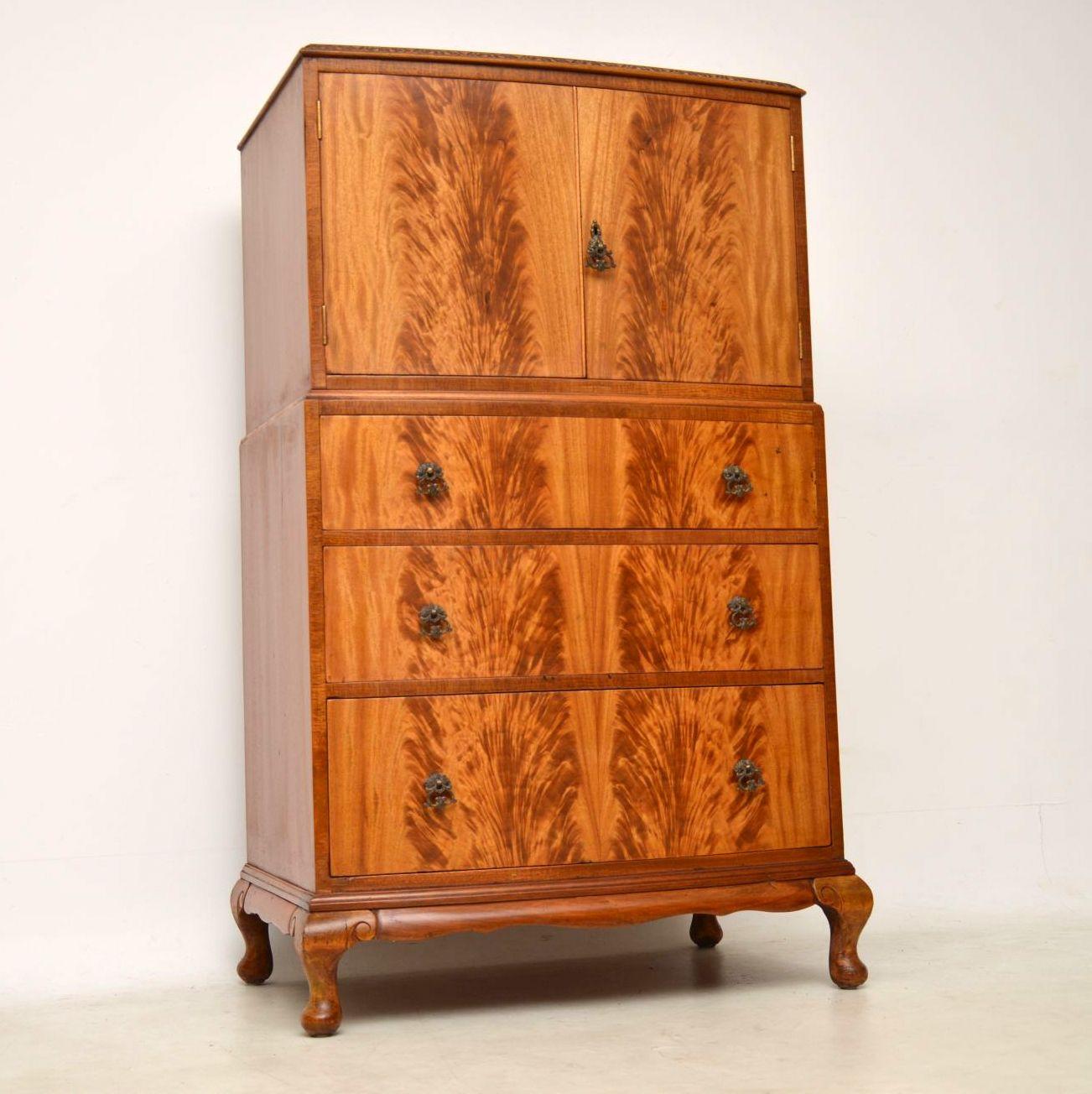 This antique cupboard on chest has some stunning flame mahogany veneers giving it a very striking pattern especially on the front and the top also has some interesting figuring. This piece is bow fronted, with a carved top edge, two top cupboards,