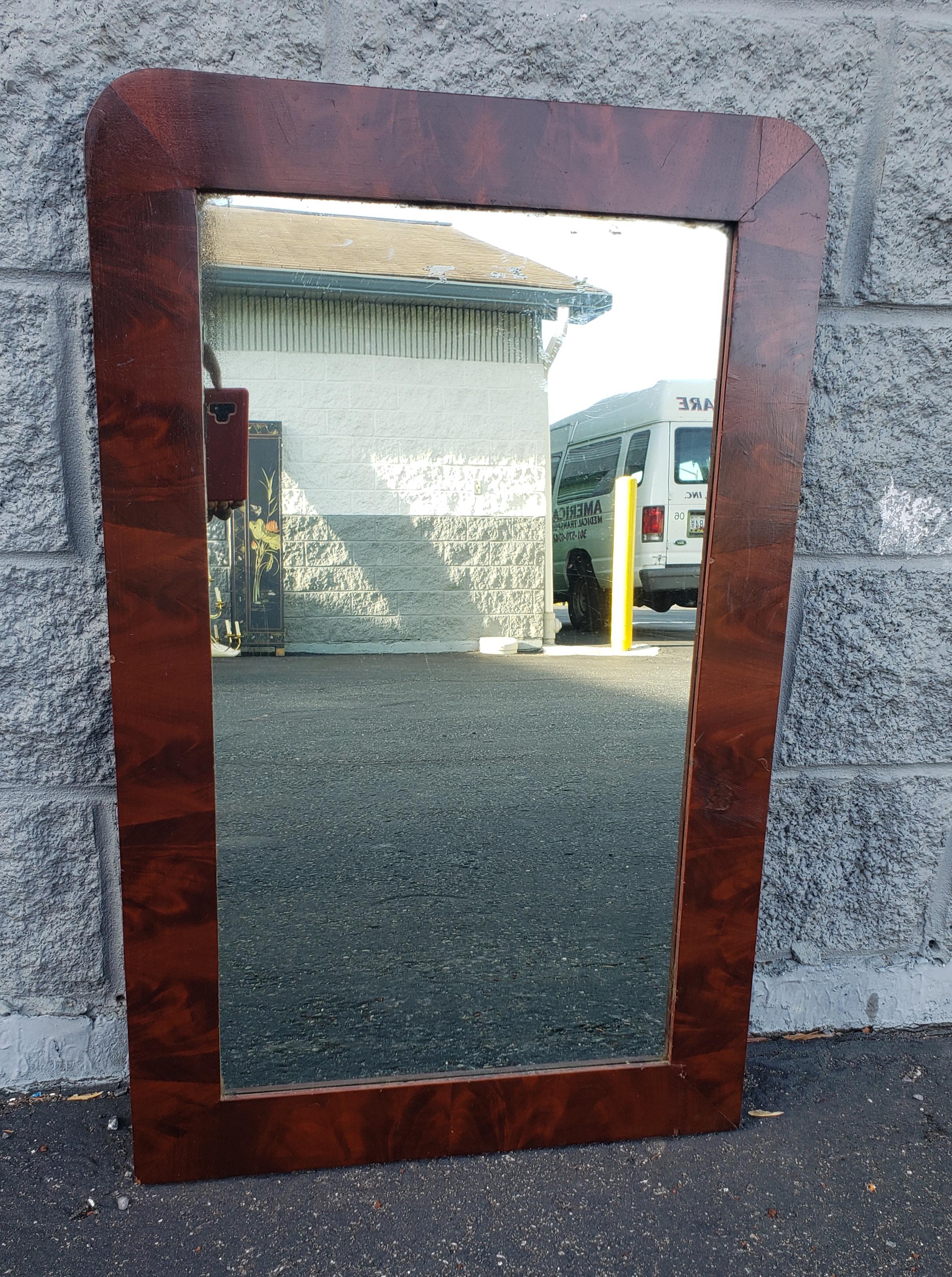 Antique flame mahogany frame wall mirror. Shows age on wood and on mirror,, but in good co dition. Measures 21.25 in width x 33.5