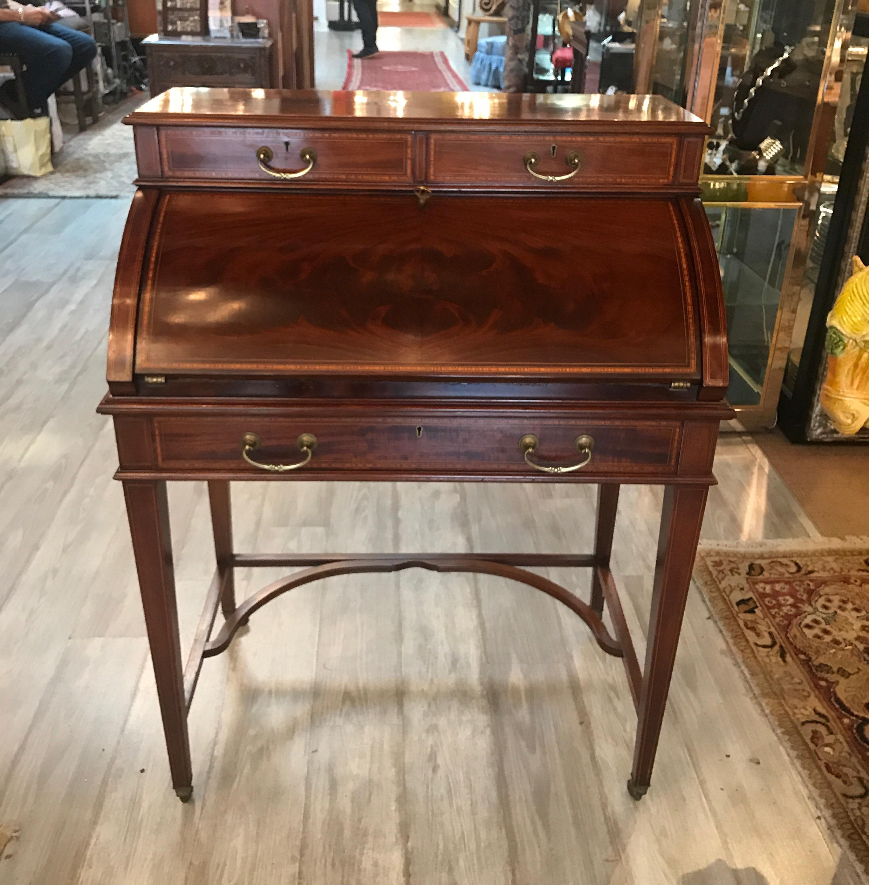 Elegant flame mahogany fall front desk with banding and inlay of satinwood and ebony. The diminutive desk with two drawers at the top and on long drawer at the apron. The front opens to reveal a storage shelf and three smaller drawers. The original