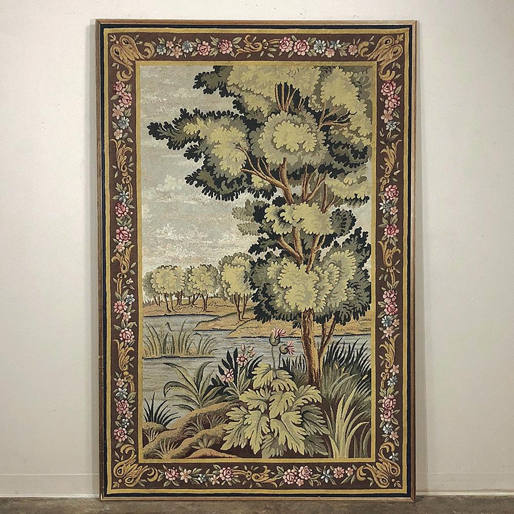 Antique Flemish Oudenaarde style framed wool tapestry features a beautiful waterside scene with abundant floral and foliate detail. Original floral and foliate border in subdued pastel colors adds a wonderful touch, protected by the subtle gold