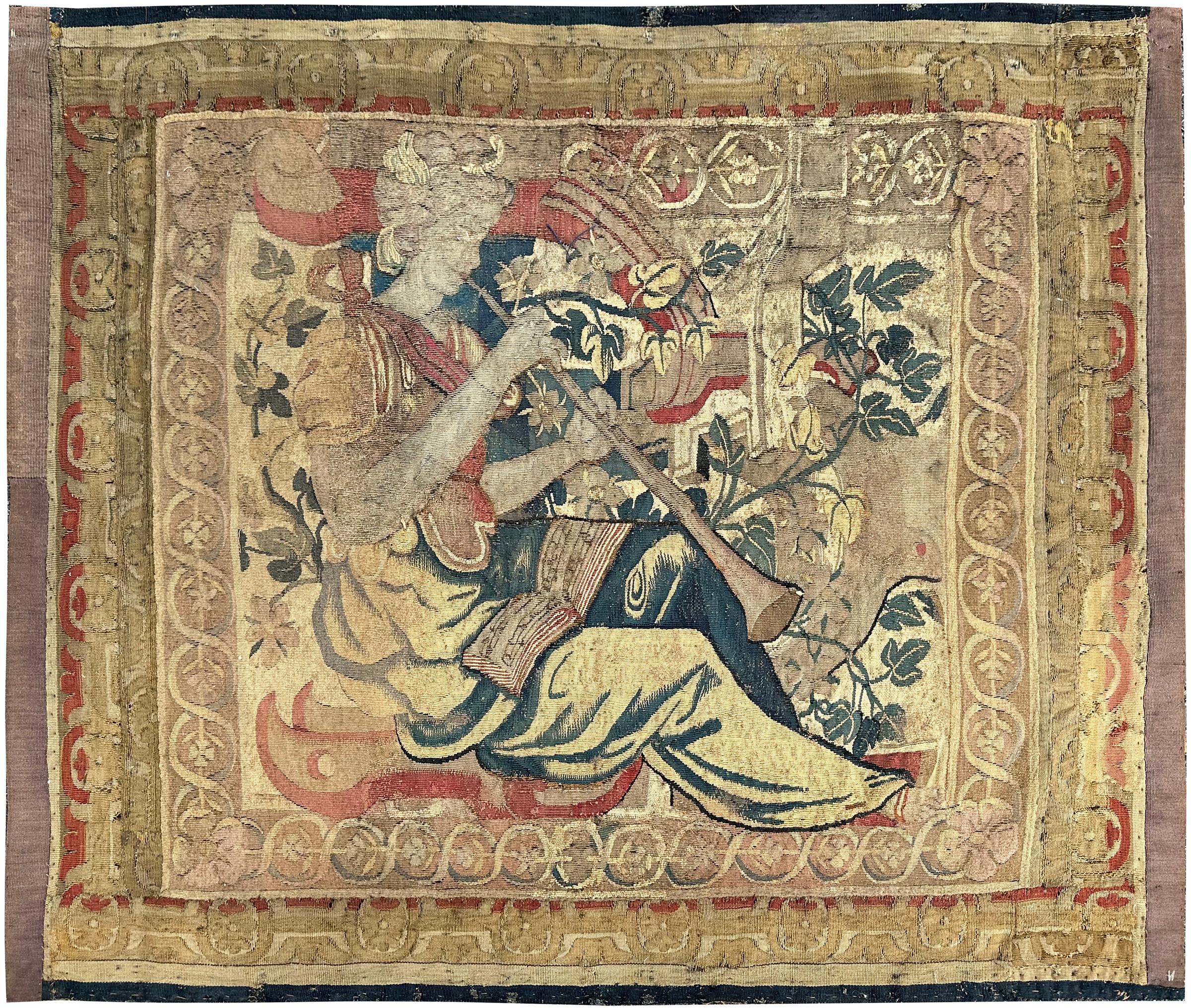 This exquisite 17th-century Flemish tapestry depicts a seated musical figure surrounded by scrolling foliage, floral motifs, and a richly detailed border. The wool and silk weave still shows vivid color contrasts and finely executed detailing