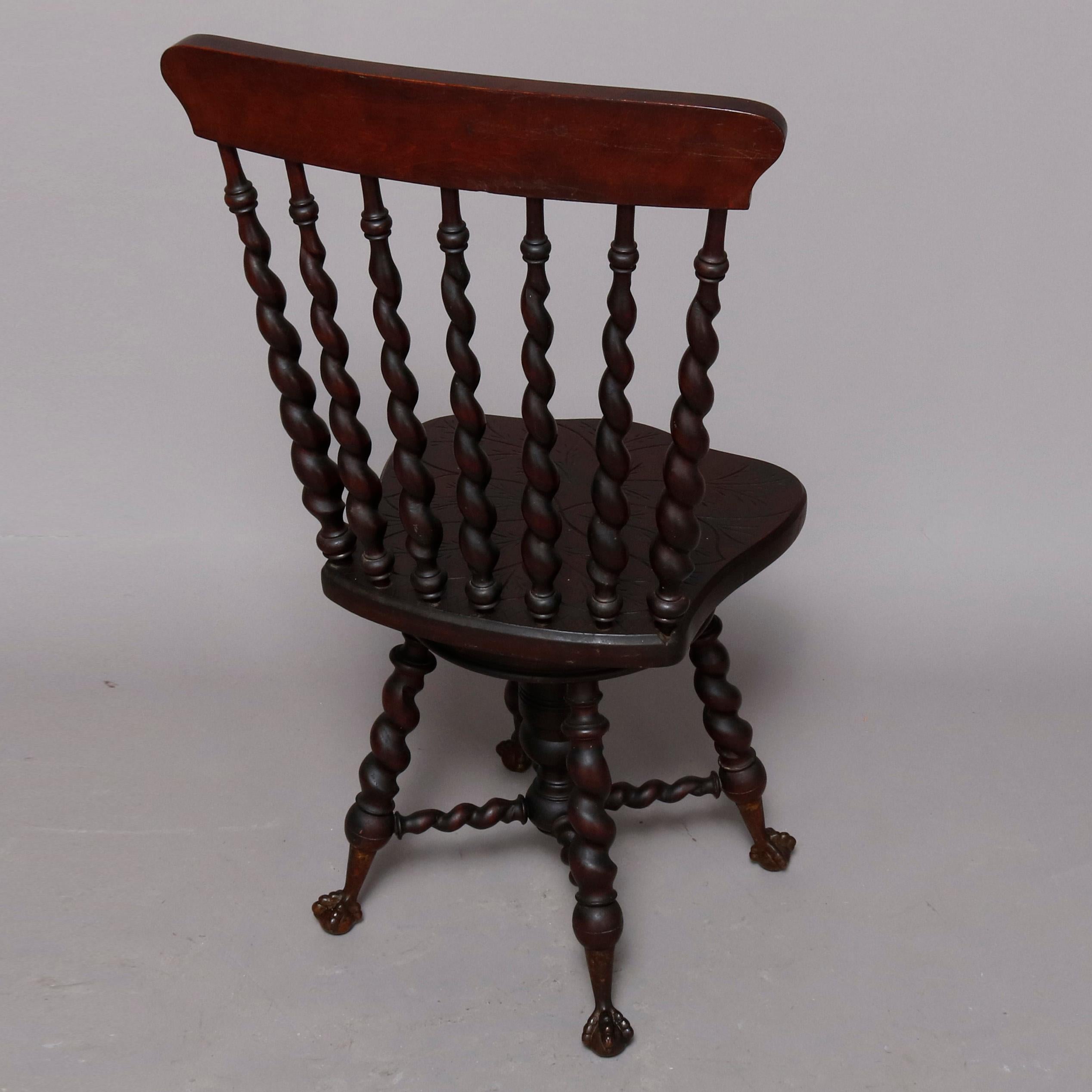 An antique Flint School piano chair features carved mahogany construction with foliate carved crest surmounting barley twist spindle back and adjustable seat, raised on flared barley twist legs terminating in claw and ball feet, circa