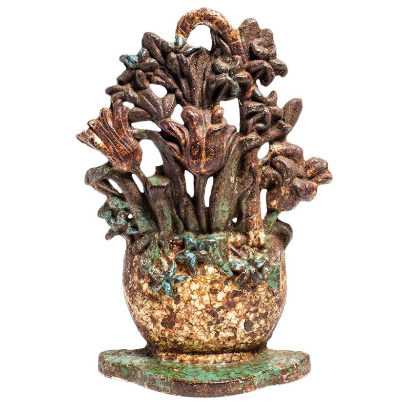 Charming cast iron doorstop with a cheerful flower basket design, made in England circa 1880. Sturdy and functional, the doorstop has a wonderful painted finish in a pastel palette.