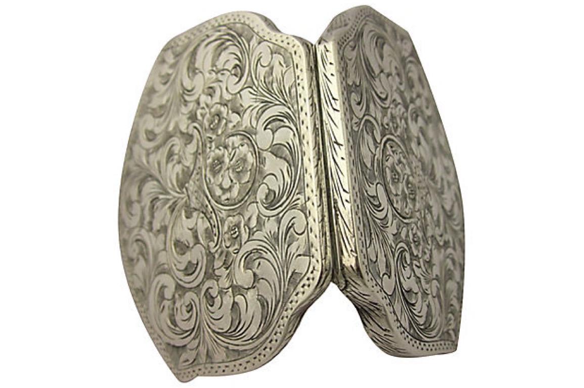 Italian 800 silver floral designed engraved compact with scalloped sides.   On both sides the compact has a basket full of flowers engraved in the middle radiating from the basket is scrolling leaves / vines. The compact has the original powder