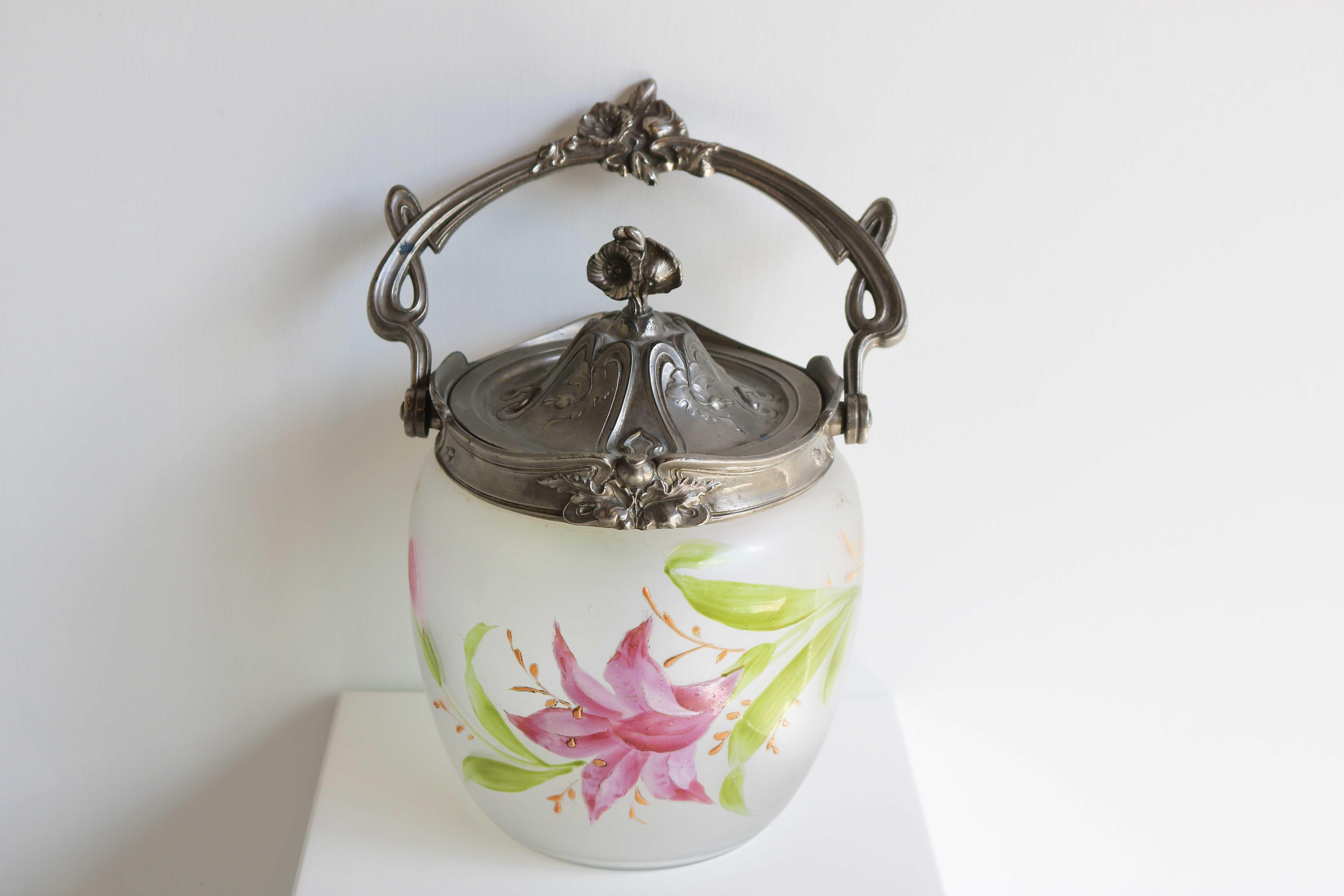 Antique floral glass biscuit barrel / cookie jar with Art Nouveau Enamel Decoration, France 1890-1919

An antique biscuit jar of frosted, satin glass with a silvered metal rim, removable top, and bail handle dating to the late 19th-early 20th