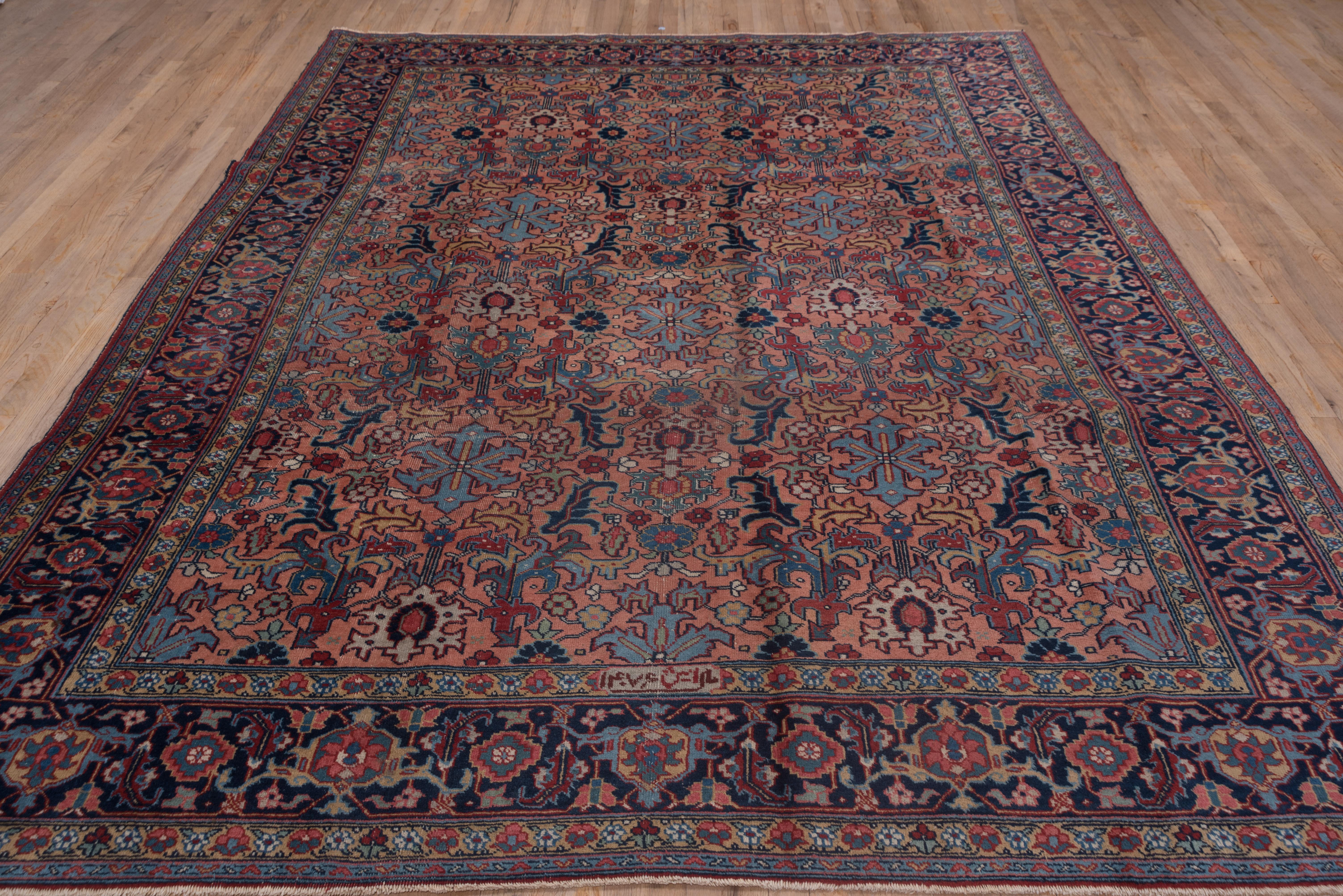 The rose field displays a dense allover pattern of leaves, fantasy flowers and hexafoils in medium blue, mustard and navy. The navy main border of this unusual NW Persian rural carpet features turtle palmettes and stepped octagons.
 