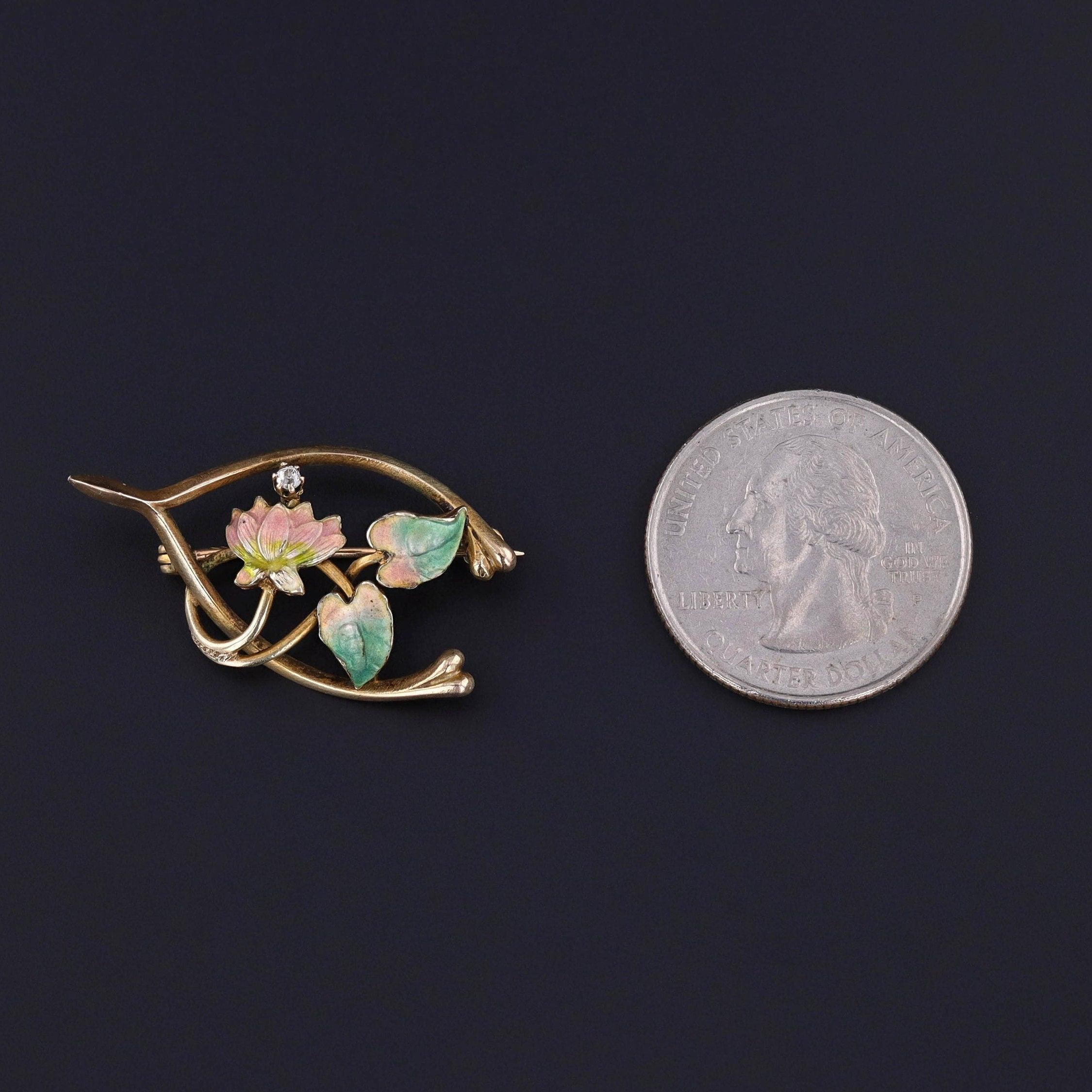 Broche de espoleta antiguo: Añade un poco de suerte a cualquier conjunto con este broche de espoleta antiguo adornado con un lirio esmaltado y un brillante acento de diamantes.

El broche de oro de 14 quilates mide 0,75 pulgadas de arriba abajo por