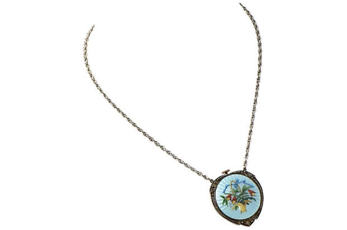 Antique pendant watch featuring a powder blue guilloche enameled case and a flower basket decoration in the center. The outside of the sterling shield shaped case is set with paste stones. Signed Sterling, Germany, and Wilhelm Becker inside case.