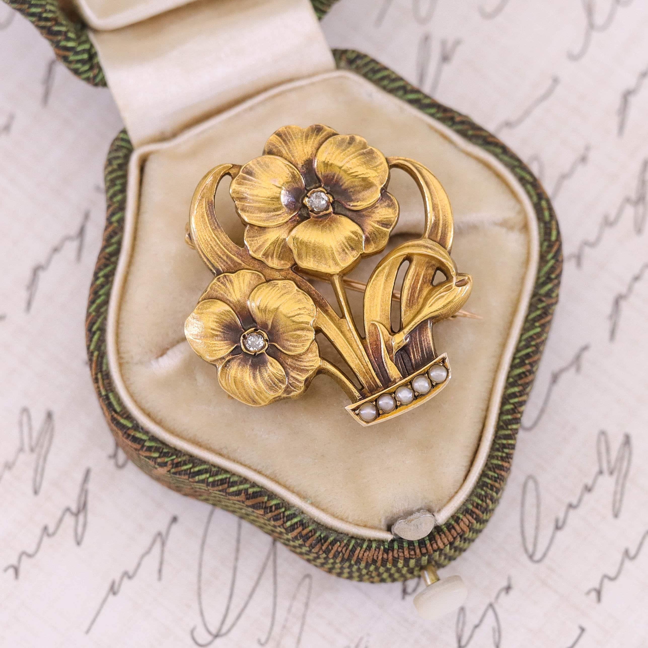 Cette broche ancienne en or 10k (vers 1900) présente deux pensées rehaussées de diamants dans un 