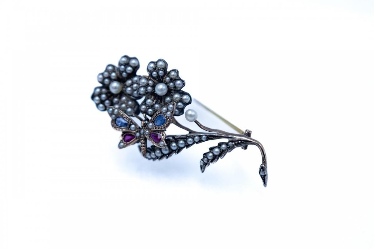 Spilla a forma di fiore in oro e argento con perle naturali e farfalla in zaffiro e rubino

Origine: Scandinavia, fine del XIX secolo

Dimensioni: larghezza 5cm x lunghezza 2,5cm

Peso del prodotto: 8.340 g

Una bellissima spilla a forma di fiore in