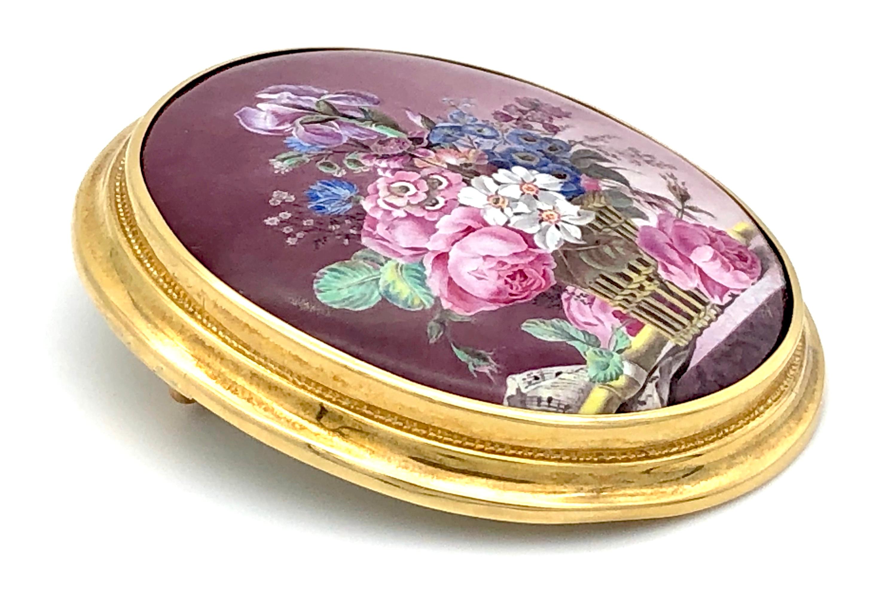A flower bouquet in a basket, a flute and a sheet of music are composed to a still life of fabulous quality. The miniature is painted on porcelain. This most amazing work of art is mounted in an exquisite 18 k gold frame and can be worn as a brooch.