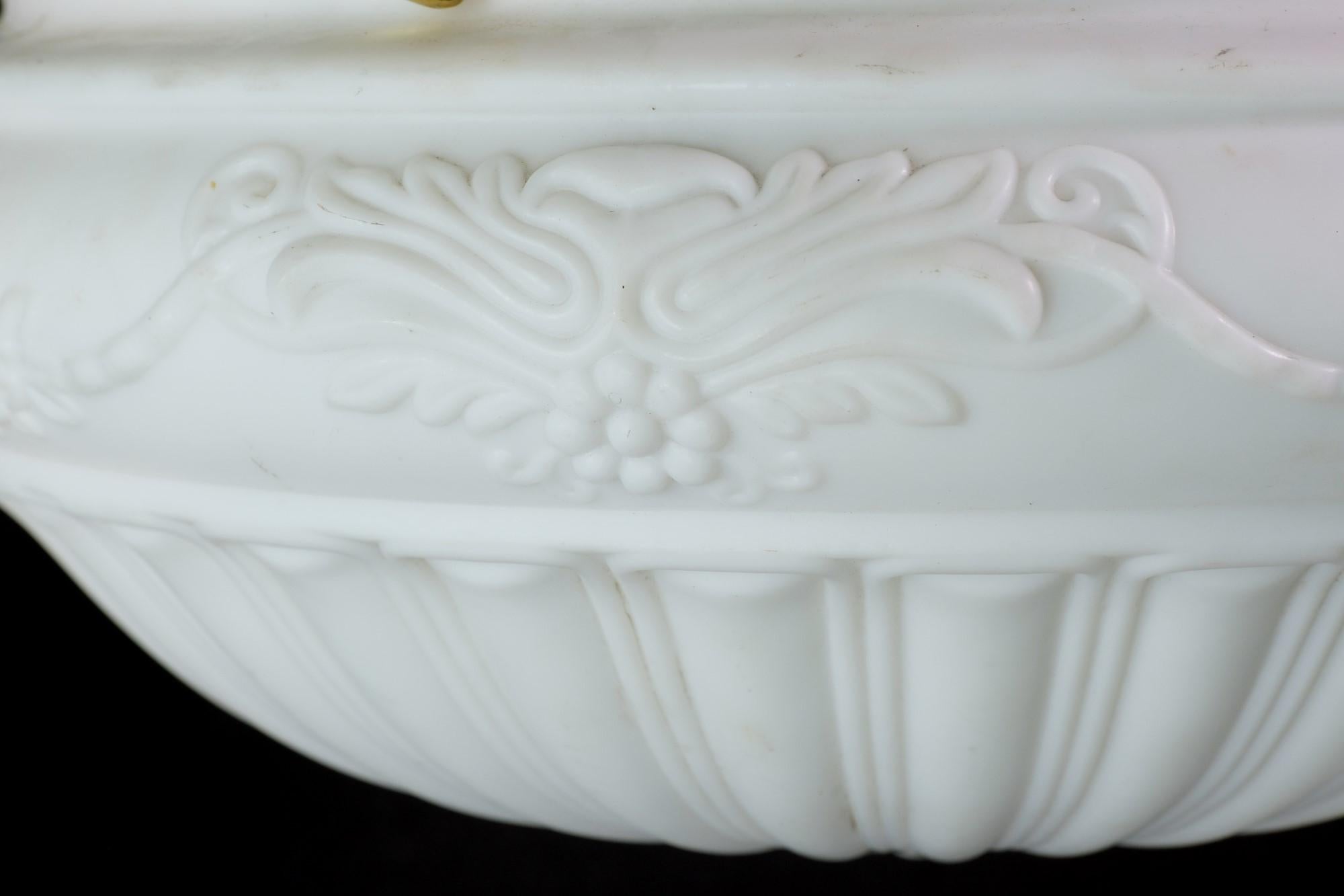 This early 1900's, Victorian style fluted cast glass pendant light has elegant floral details and is suspended by a brass fitter. It has a white color with a bisque-like flat finish. The price includes restoration.