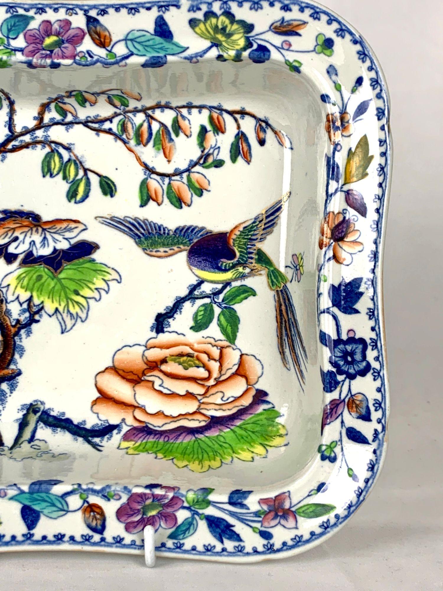 This antique Davenport rectangular dish is decorated in the vibrant Flying Bird pattern.
The design features a colorful, long-tailed bird flying over a lush garden of chinoiserie flowers.
Painted in a vivid palette of purple, pink, yellow, orange,
