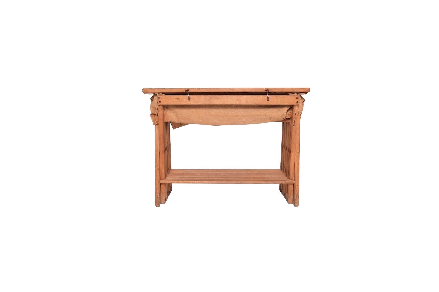 An exceptional Victorian folding campaign bed that cleverly doubles as a compact side table or console when not in use. Dating to the late 19th century, this British military piece features a solid oak X-frame base that folds accordion-style into a