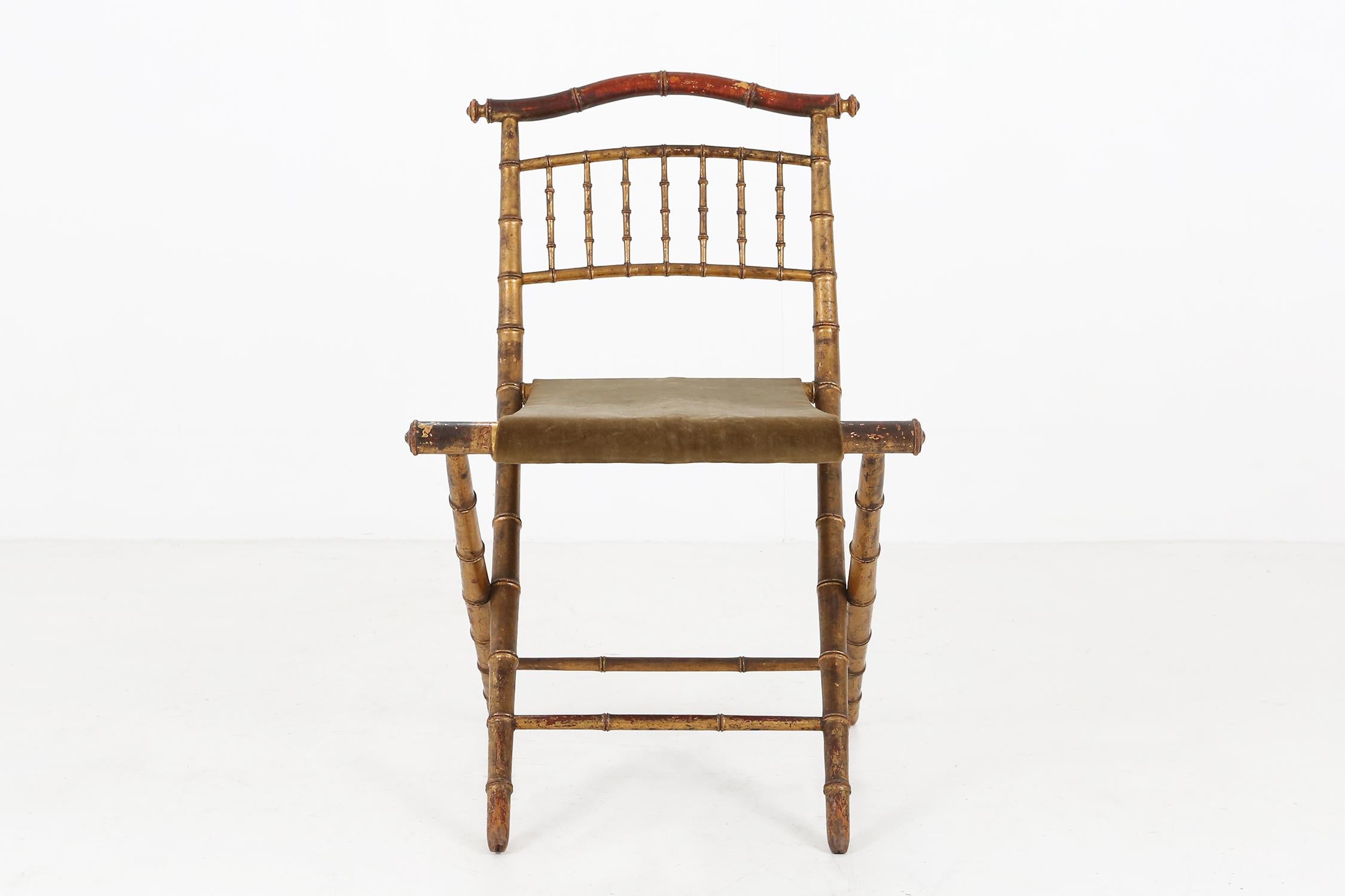 Ancienne chaise pliante en faux bambou de couleur or doré et tissu vert.
Très belle patine.