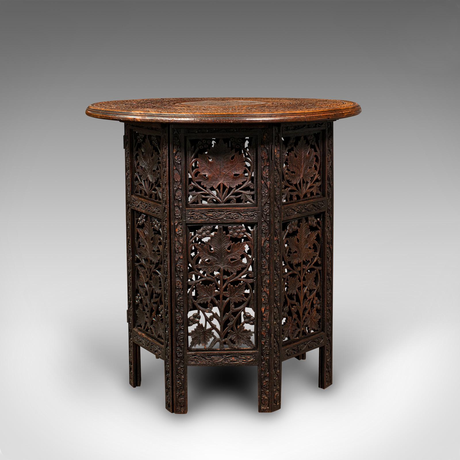 This is an antique folding Colonial table. An Anglo-Indian, teak occasional or side table, dating to the Victorian period, circa 1900.

Enthusiastically pierced fretwork upon an unusual, heptagonal folding form
Displays a desirable aged patina in