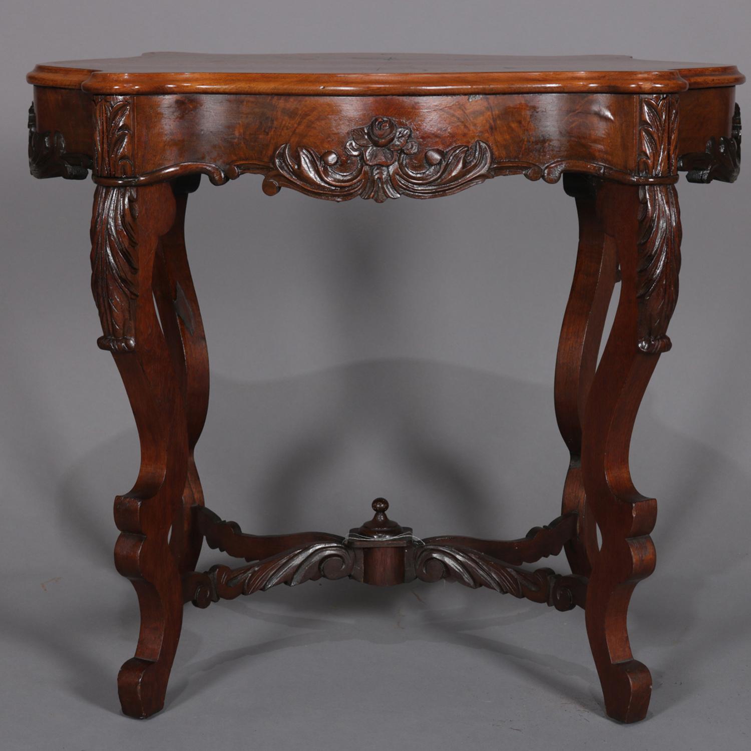Antique center table features carved burl walnut construction with shaped and beveled top over scalloped skirt with central carved foliate and floral reserves raised on acanthus carved s-scroll legs surmounting c-scroll feet and having acanthus form