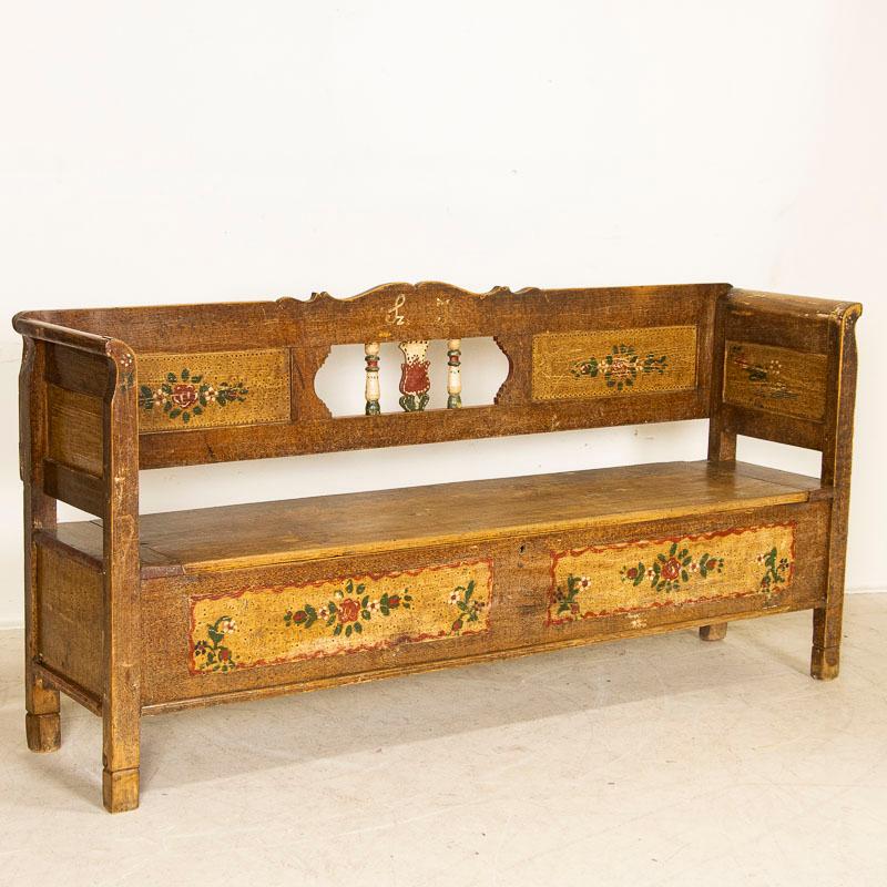 The quality and craftsmanship of this pine bench are exceptional with its traditional Eastern European Folk Art painted motifs. The red painted flowers and delicate spindle and carved center add to its country charm. The warm patina of this bench is