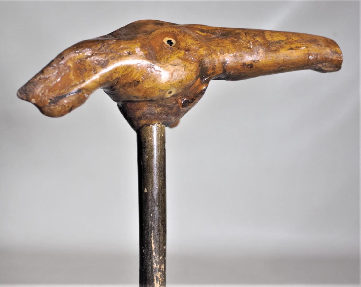 This Folk Art cane or walking stick is completely unmarked, but presumed to have been made in the United States in circa 1920 in the Folk Art style. The handle of the cane is a lacquered piece of burled wood that may have been intended to resemble