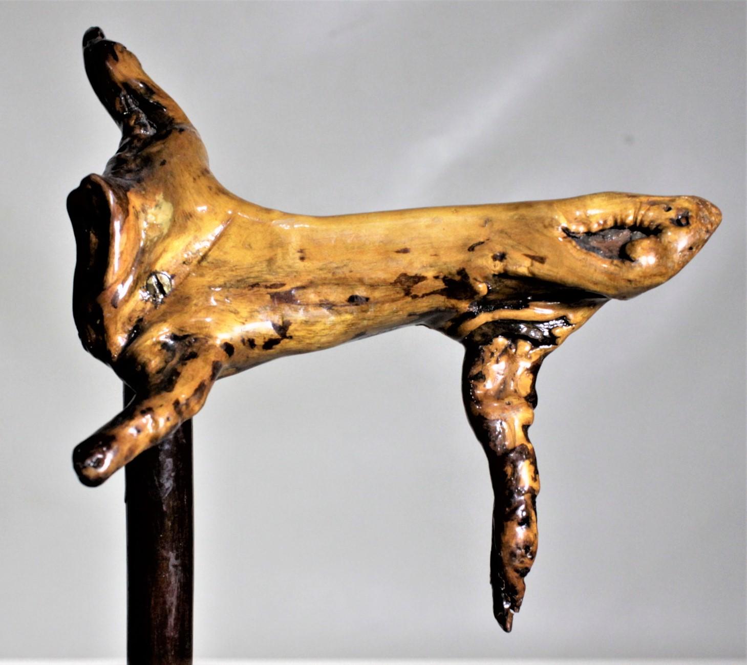 This Folk Art cane or walking stick is completely unmarked, but presumed to have been made in the United States in circa 1920 in the Folk Art style. The handle of the cane is a lacquered piece of burled wood with unconventional sections jettisoning